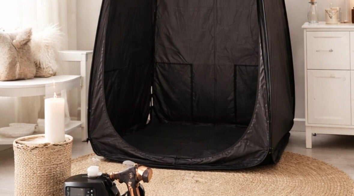 Spray tanning setup at Golden Edit in Surrey, British Columbia, CA, featuring a sleek black tent and cozy decor.