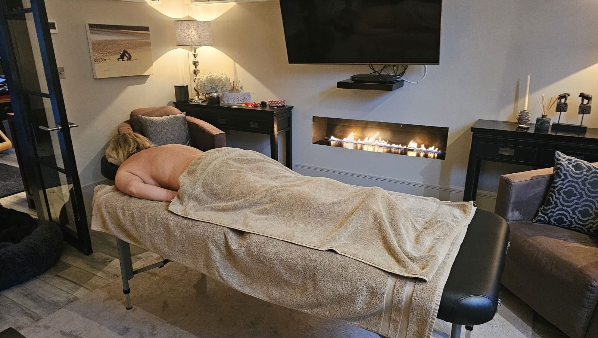 Cozy massage room at Healing Hands by Lisena LTD in London, England, GB, featuring a warm and relaxing fireplace.