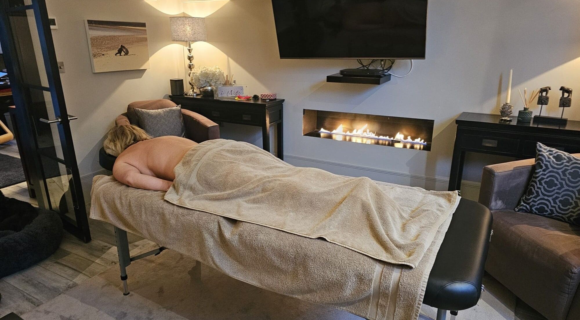 Cozy massage room at Healing Hands by Lisena LTD in London, England, GB, featuring a warm and relaxing fireplace.