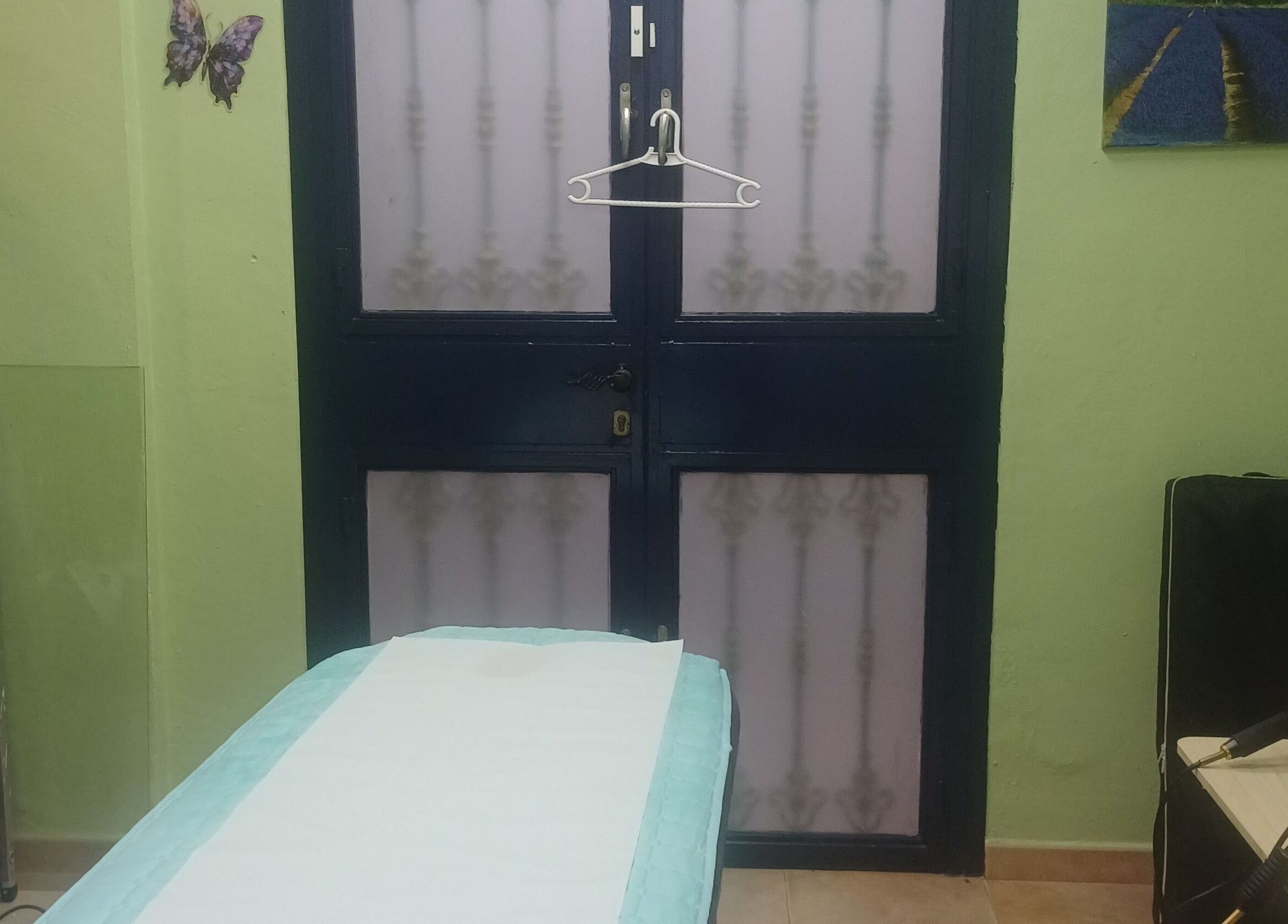 Calming therapy room at ASCENT-THERAPIES AT ALORA, MALAGA, ANDULUCIA, ES with a treatment bed and green walls.