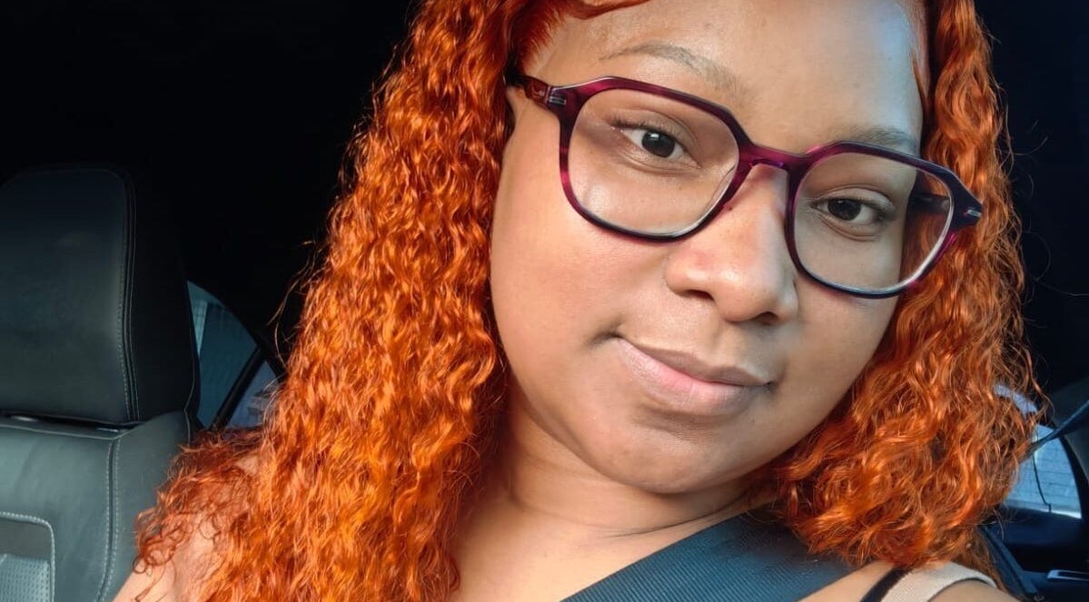 Close-up of a woman with vibrant curly orange hair at Nathari Beauty Studio, Durban, ZA.