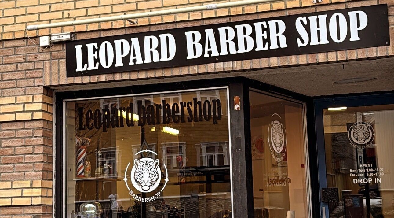 Inngang til Leopard Barbershop i Trondheim, Trøndelag, NO. Stilfull barberskilt mot murvegg.