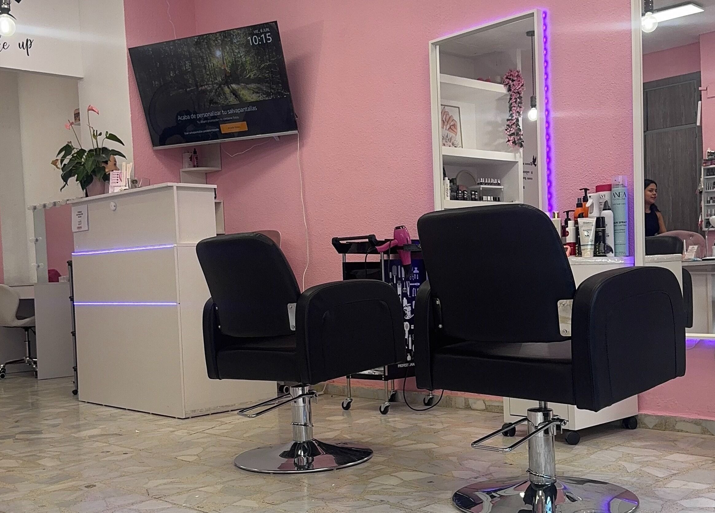 Interior moderno de Centro De Belleza Pifferrer en Alcalá De Henares, Comunidad De Madrid, ES, con sillas negras y espejo iluminado.