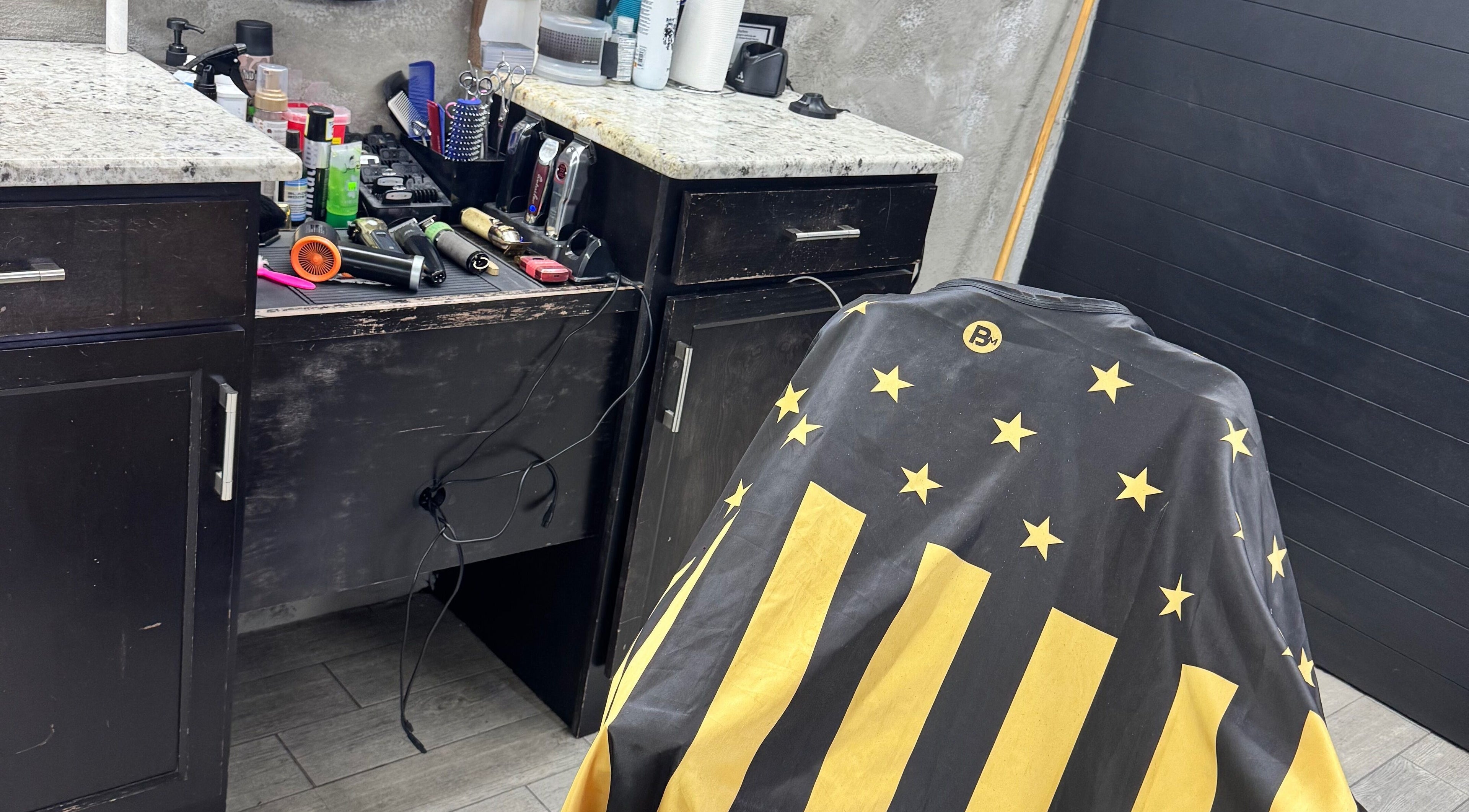 Inside Rudy the barber, Phoenix, Arizona, US showcasing tools and star-lined apron in stylish decor.