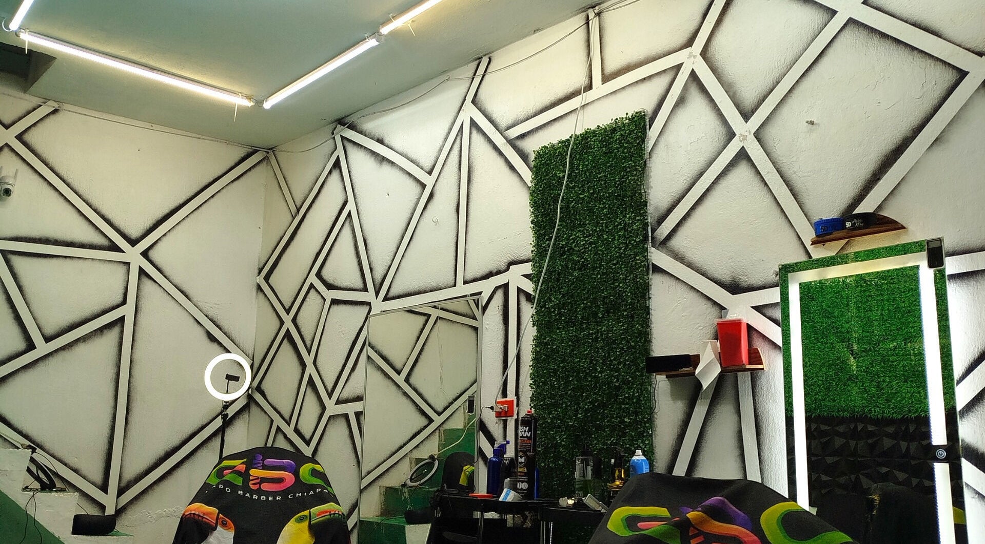 Interior moderno de Barbería Joss en Ocosingo, Chiapas, MX. Decoración geométrica y espejo iluminado.