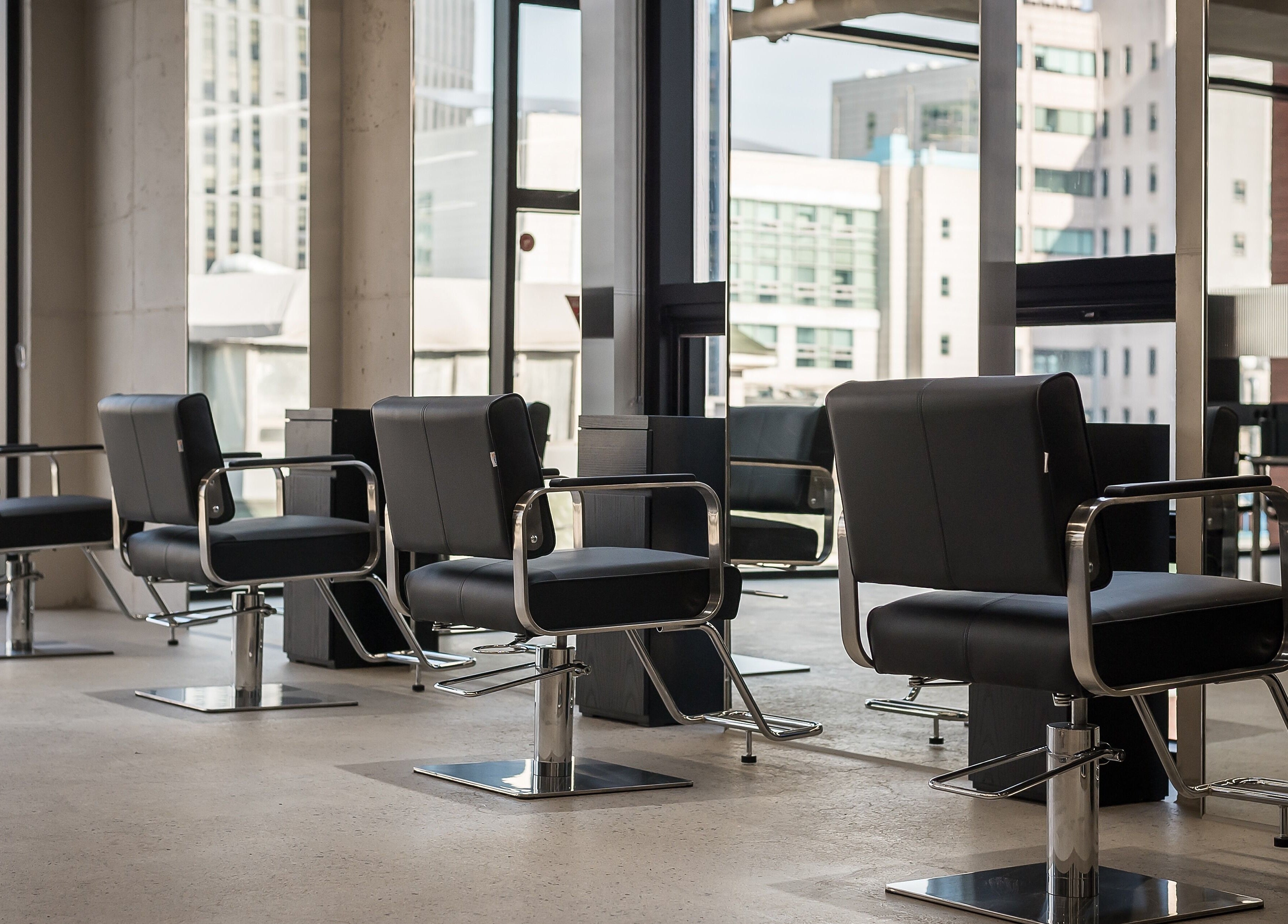 Sleek salon chairs at Dayer in 서울특별시, 서울특별시, KR, with urban cityscape view.