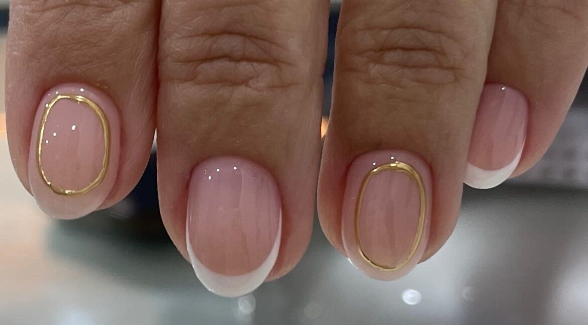 Close-up of a chic nail design at Nailz, Guaynabo, PR featuring pink polish with gold accents.