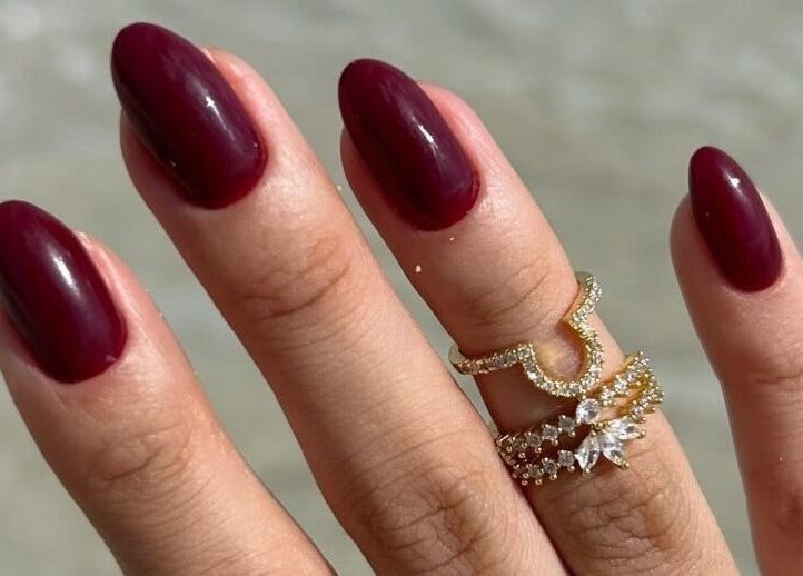 Close-up of elegant crimson nails with rings at Nailz, Guaynabo, PR, PR enhancing beauty and style.