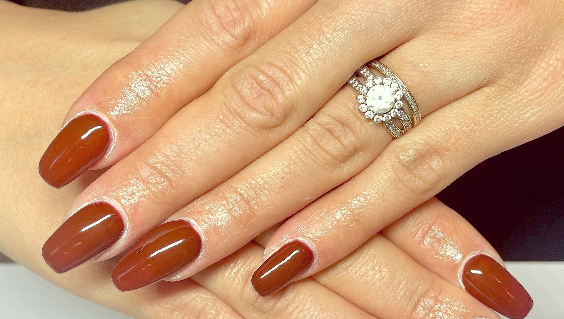 Manucure élégante aux ongles brun à Noddy Nails, Baho, Occitanie, FR, accentuée par une bague scintillante.