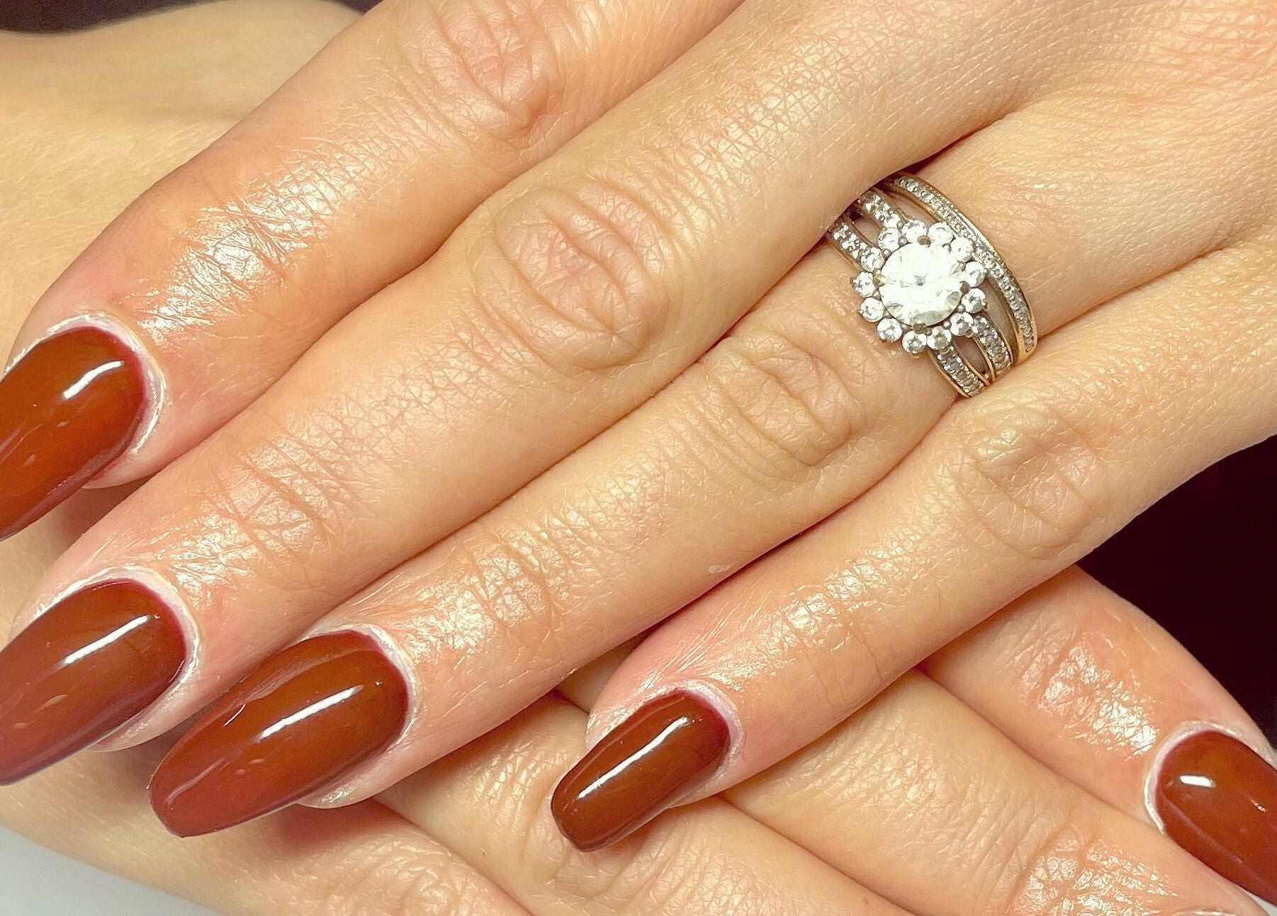 Manucure élégante aux ongles brun à Noddy Nails, Baho, Occitanie, FR, accentuée par une bague scintillante.