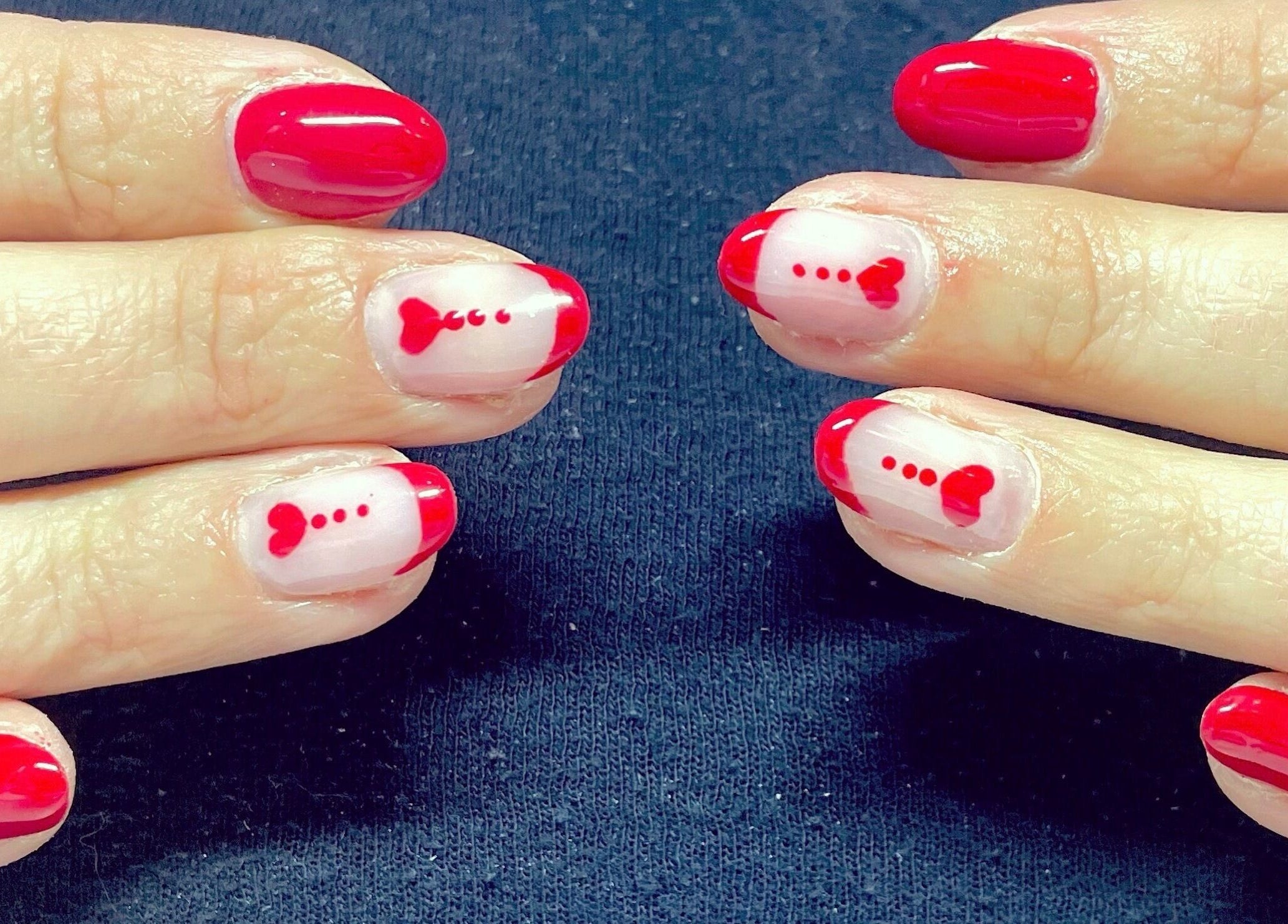 Des ongles avec une manucure rouge et des motifs cœurs à Noddy Nails, Baho, Occitanie, FR.