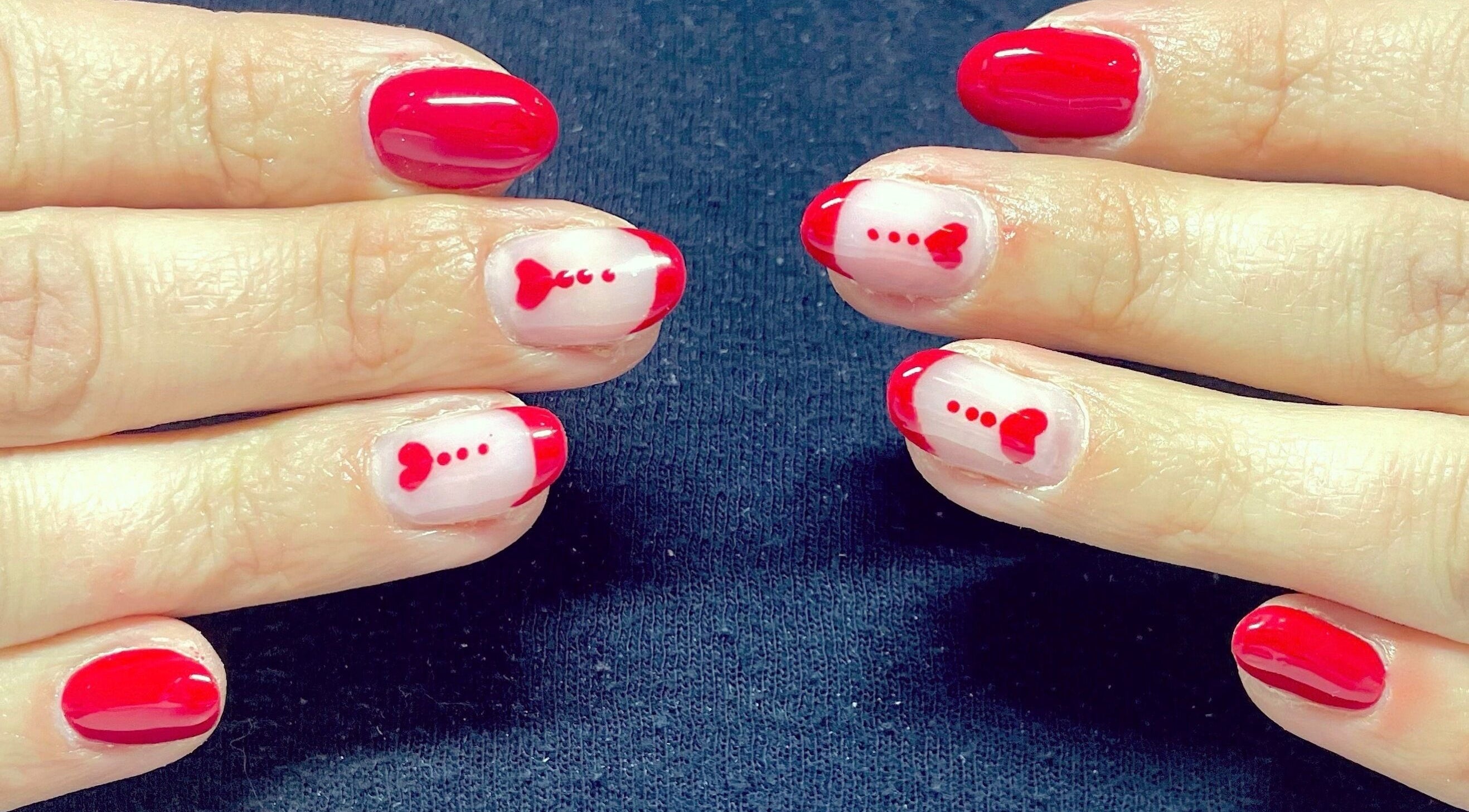 Des ongles avec une manucure rouge et des motifs cœurs à Noddy Nails, Baho, Occitanie, FR.