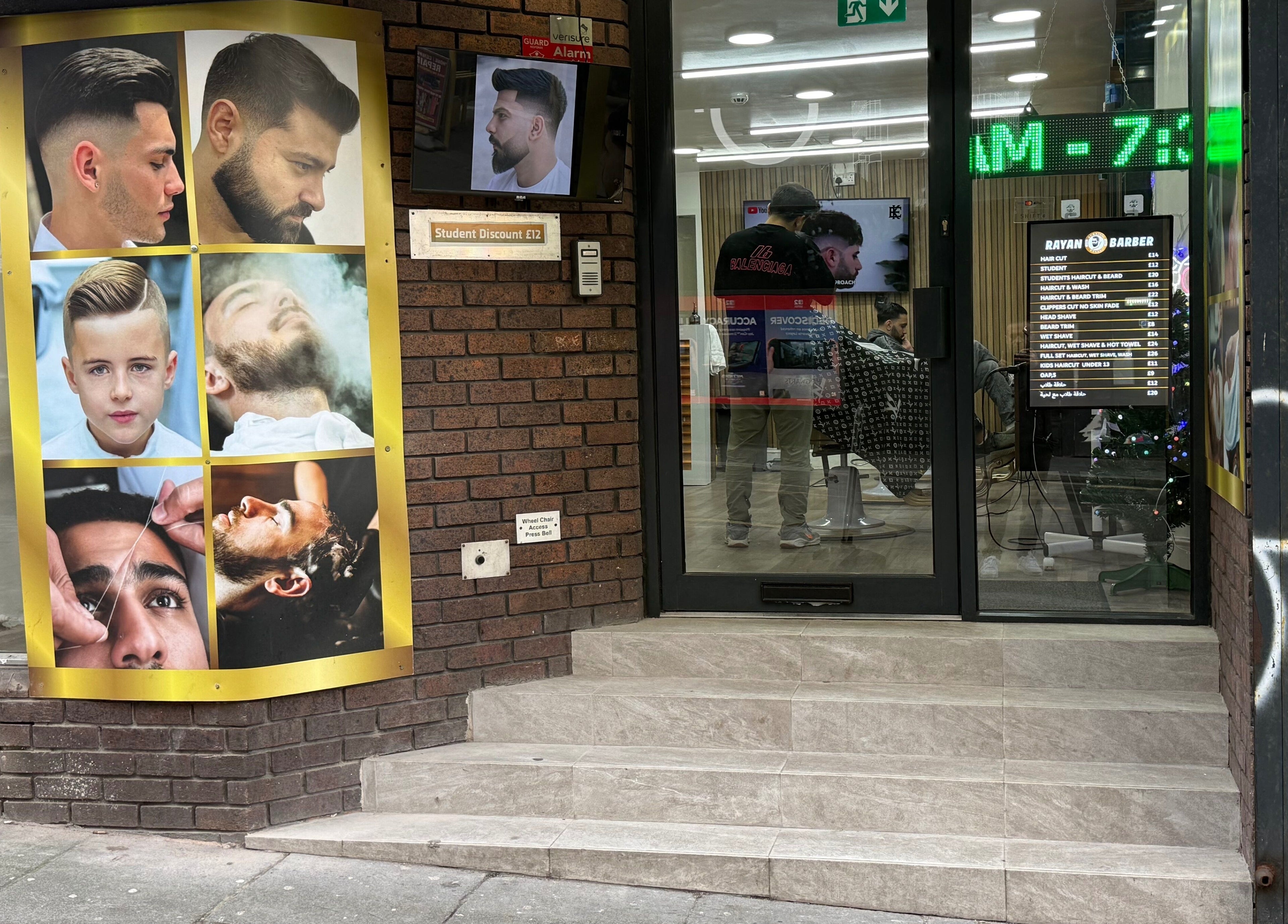 Entrance of Rayan Barber in Liverpool, England, GB with modern hair style posters displayed.