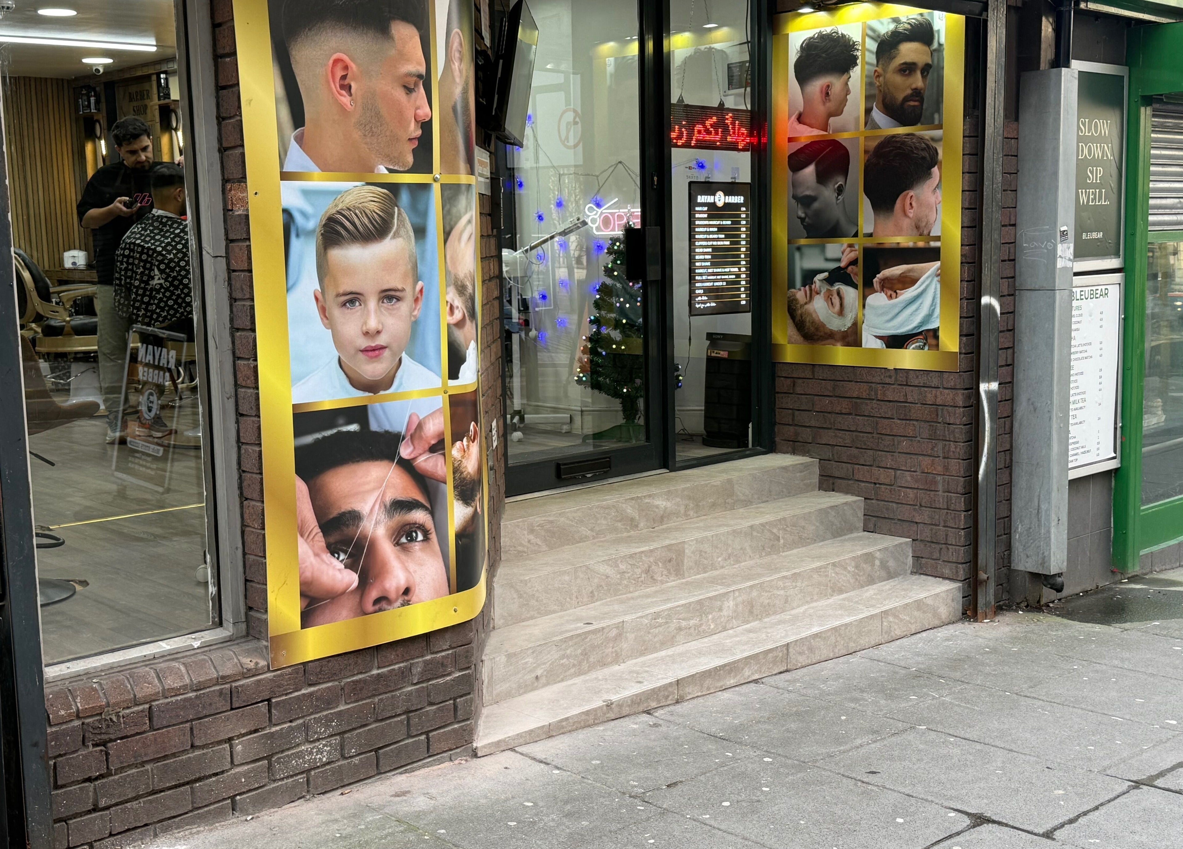 Front view of Rayan Barber in Liverpool, England, GB, with stylish hair design posters displayed outside.