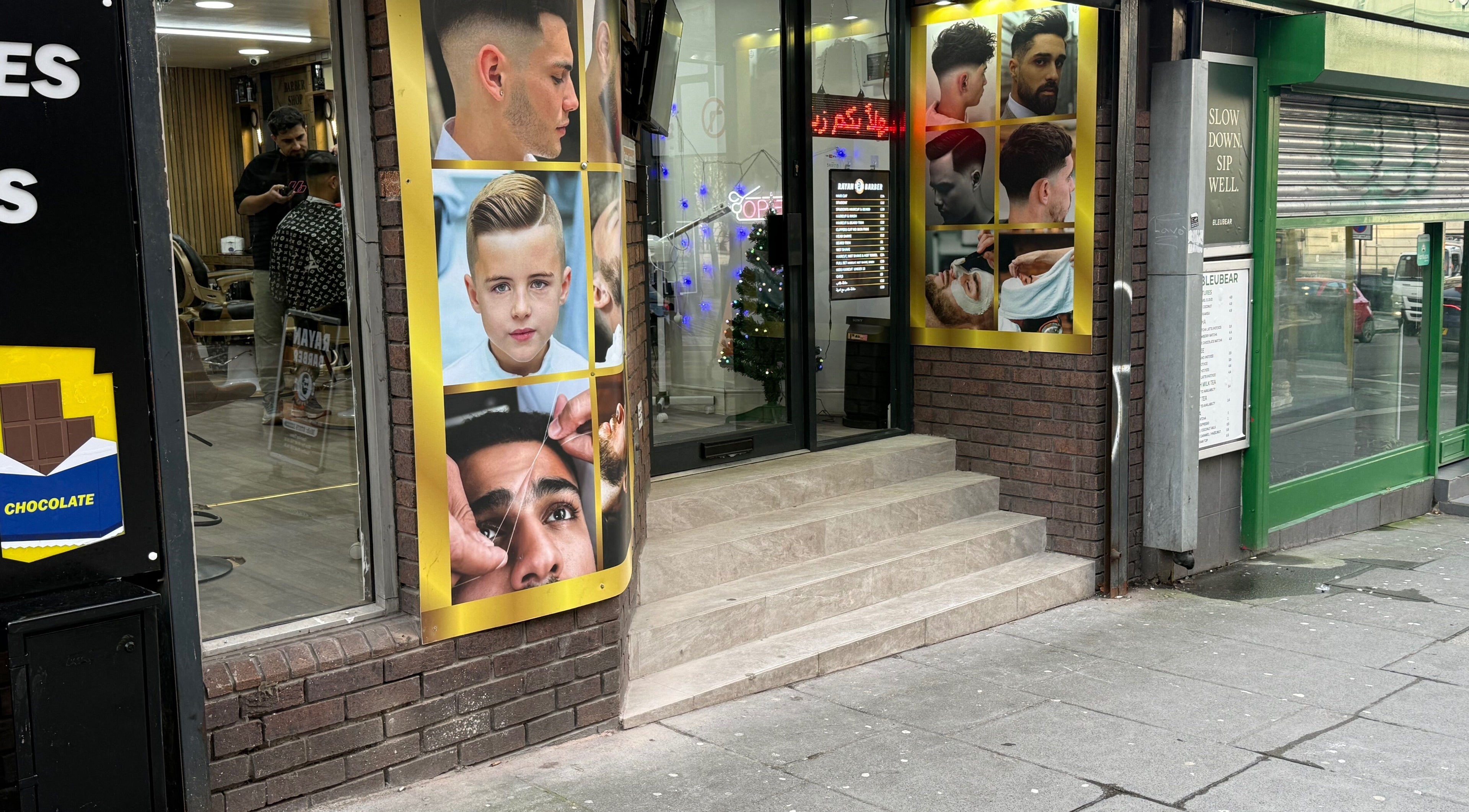 Front view of Rayan Barber in Liverpool, England, GB, with stylish hair design posters displayed outside.