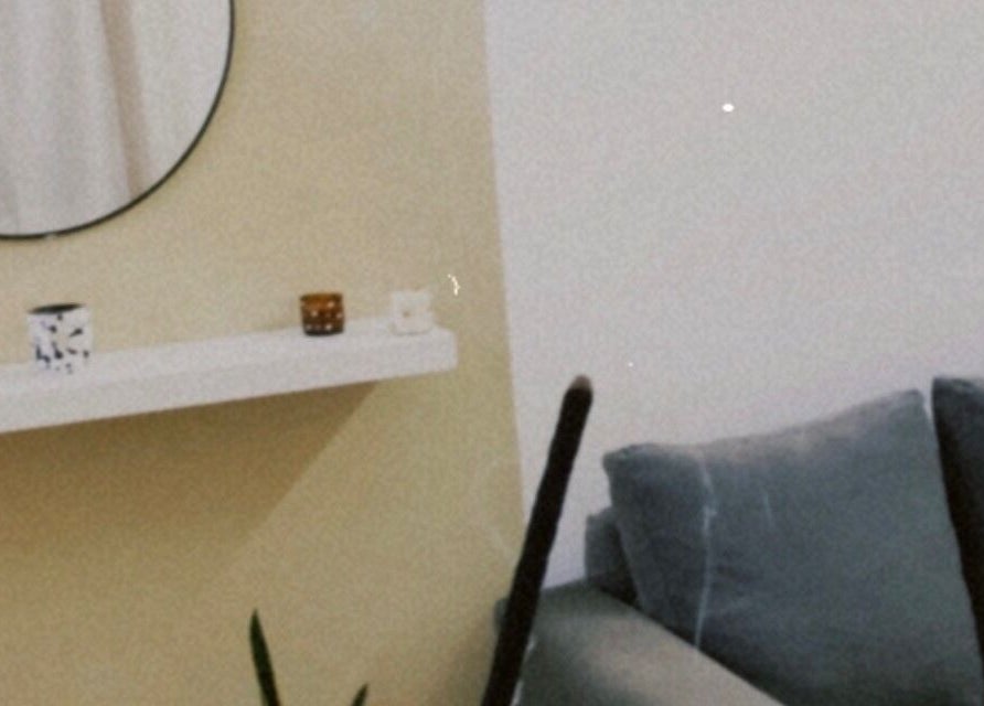 Elegante sala de espera en Poppylashess, Dolores, Provincia De Buenos Aires, AR con sofá gris y espejo decorativo.