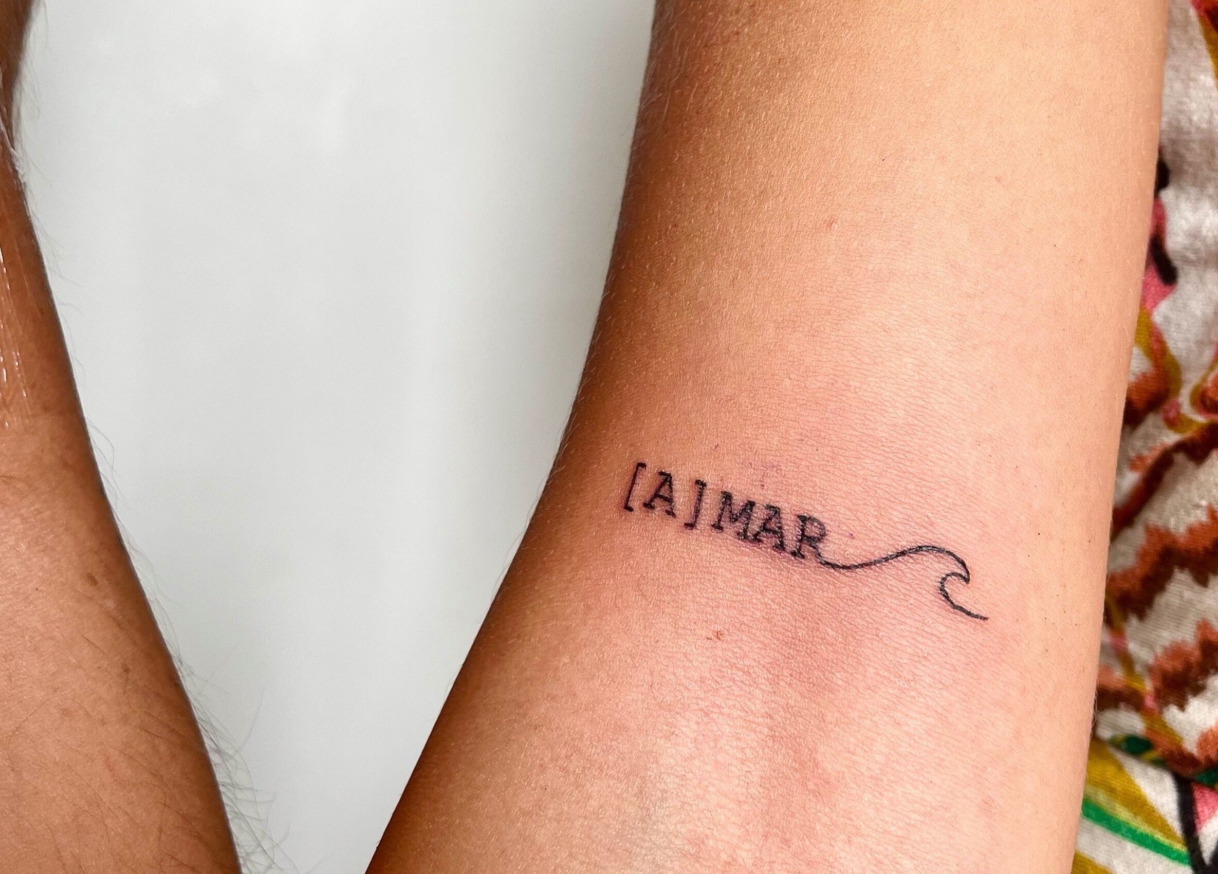 Close-up of a minimalist [A]MAR wave tattoo on forearm at Ommni Tattoo, Concón, Valparaíso, CL.