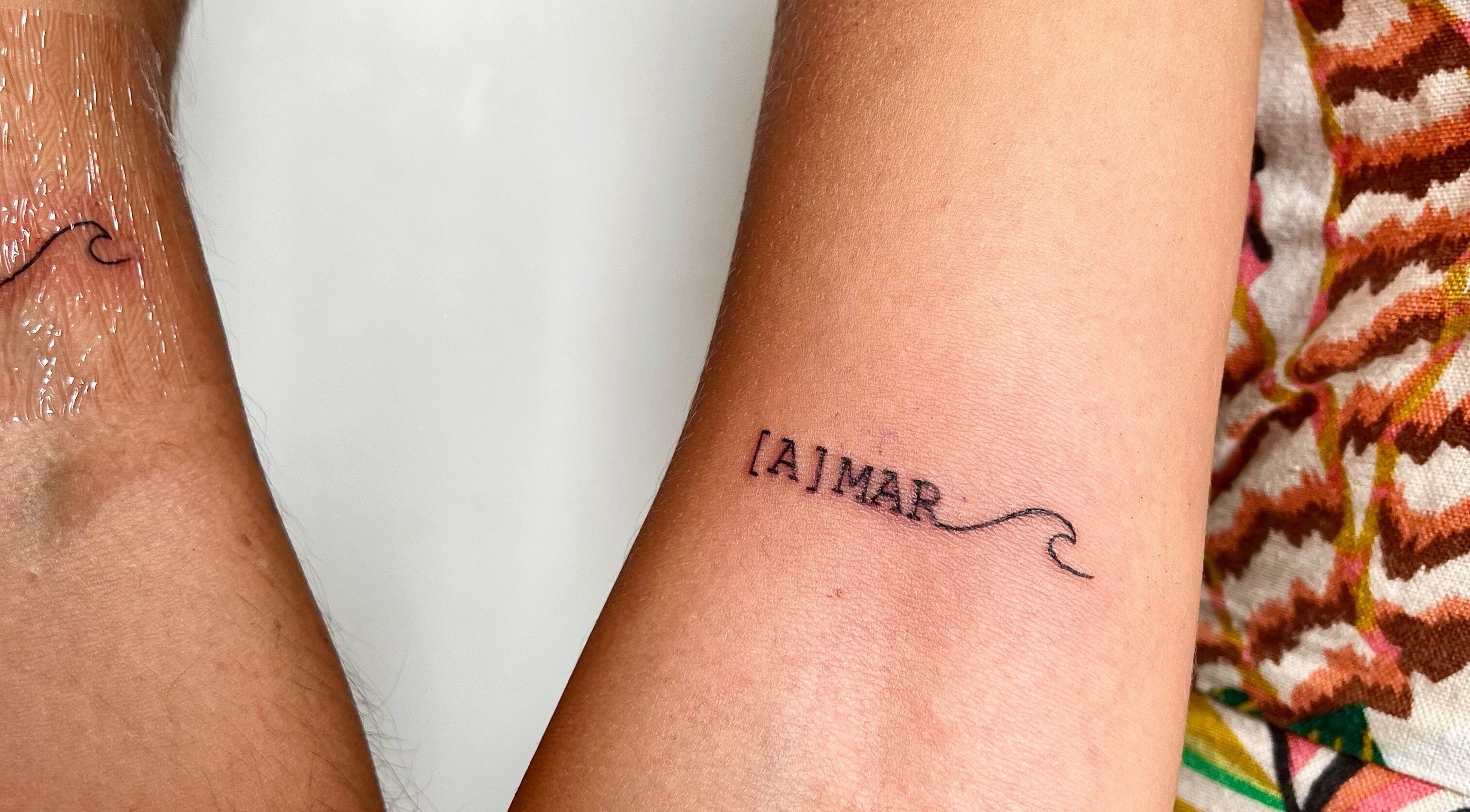 Close-up of a minimalist [A]MAR wave tattoo on forearm at Ommni Tattoo, Concón, Valparaíso, CL.