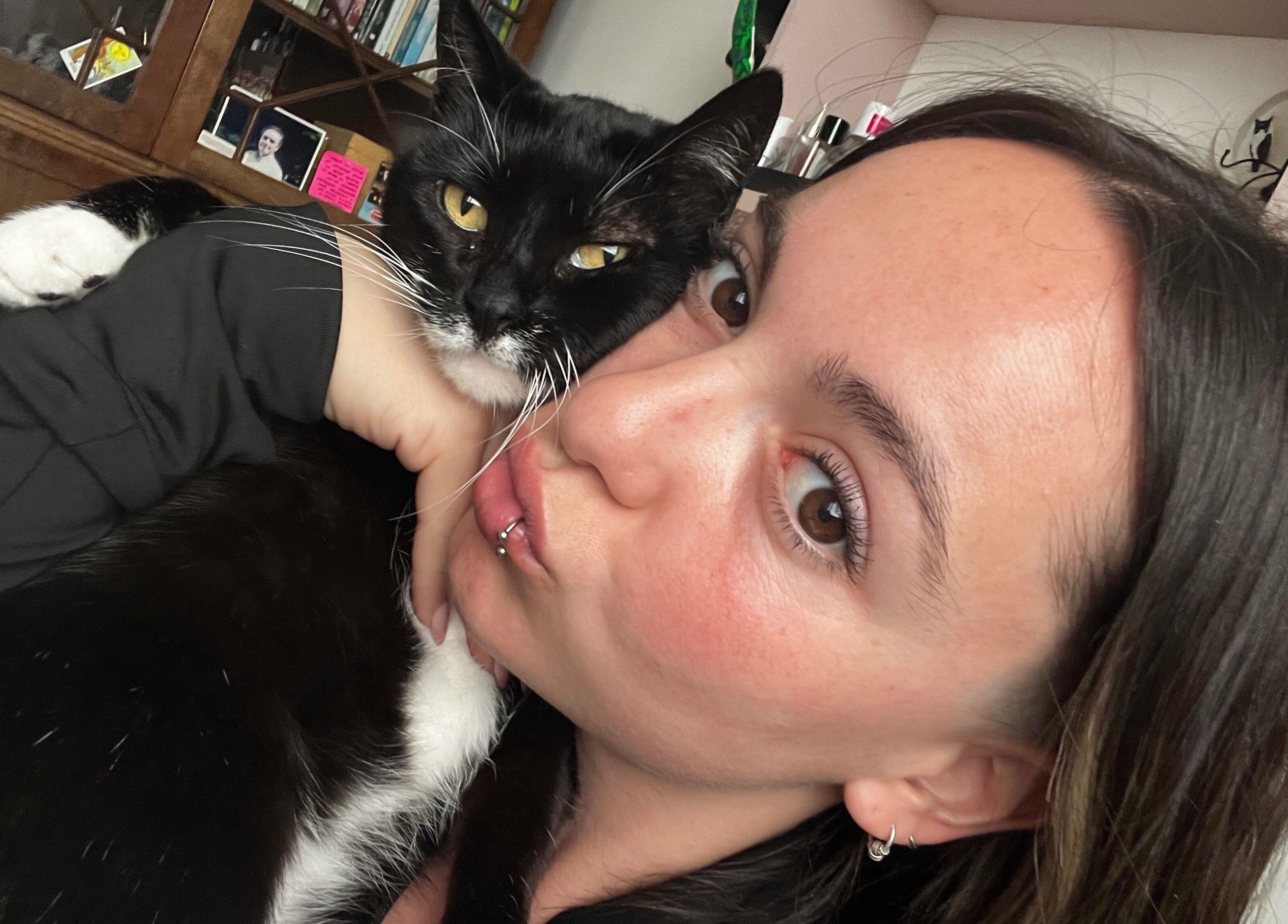 Person cuddling a cat indoors at Ommni Tattoo, Concón, Valparaíso, CL, creating a cozy atmosphere.