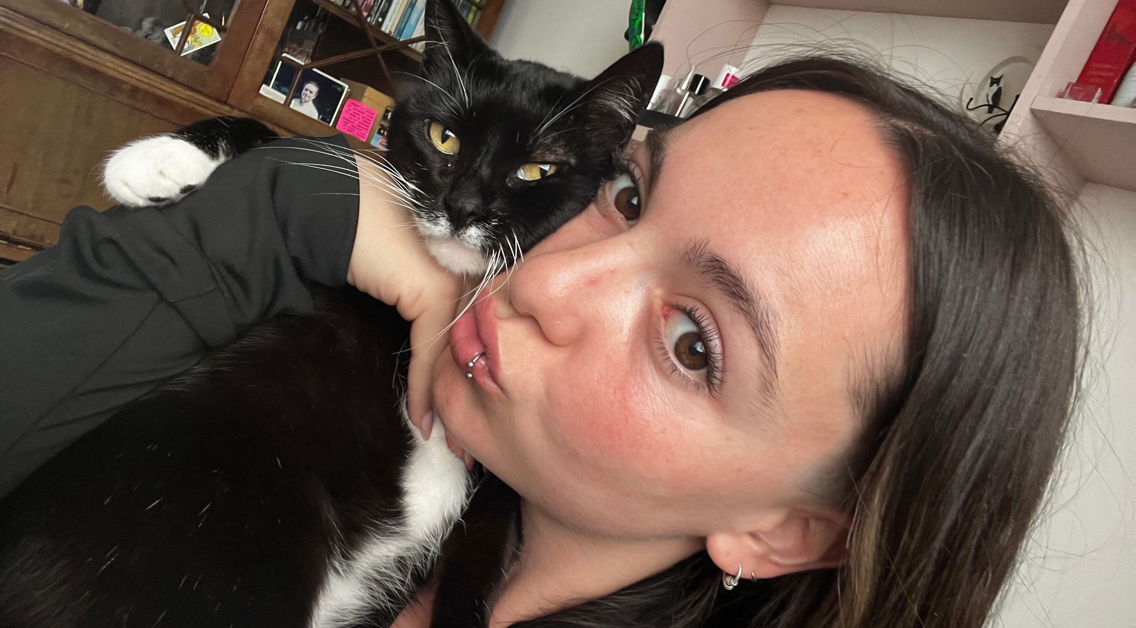 Person cuddling a cat indoors at Ommni Tattoo, Concón, Valparaíso, CL, creating a cozy atmosphere.