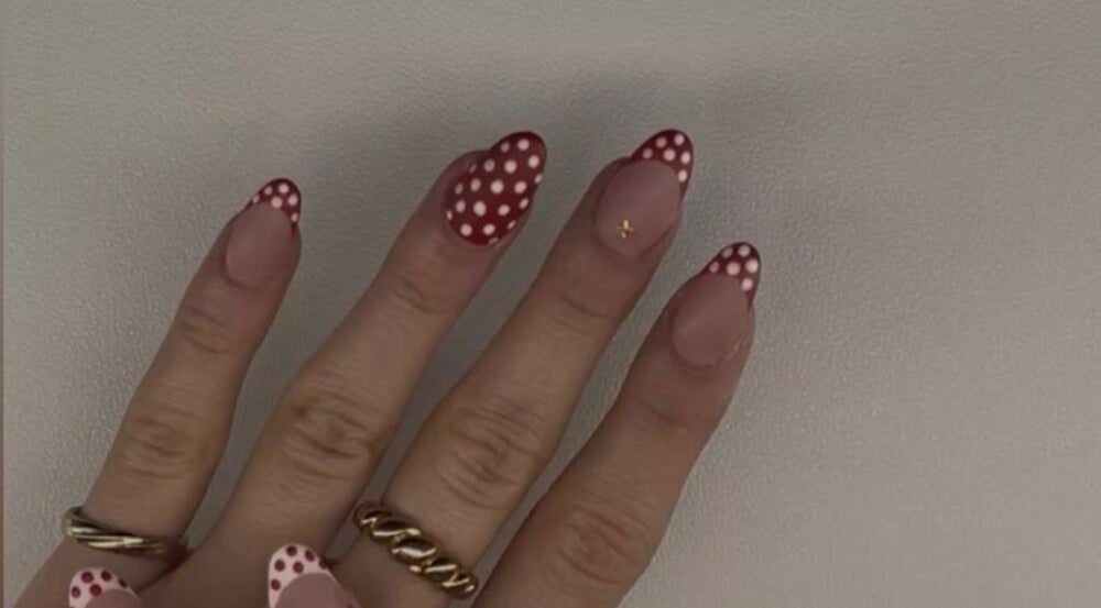 Stylish red polka dot nail art by Nails by Ela in Blainville, Québec, CA, showcasing intricate hand design.
