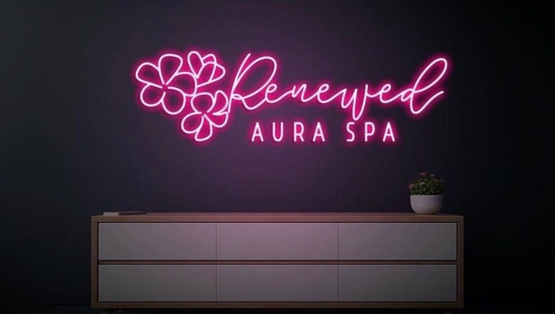 Vibrant neon sign of RAS at Gainesville, Virginia, US, glowing in pink above a minimalist white cabinet.