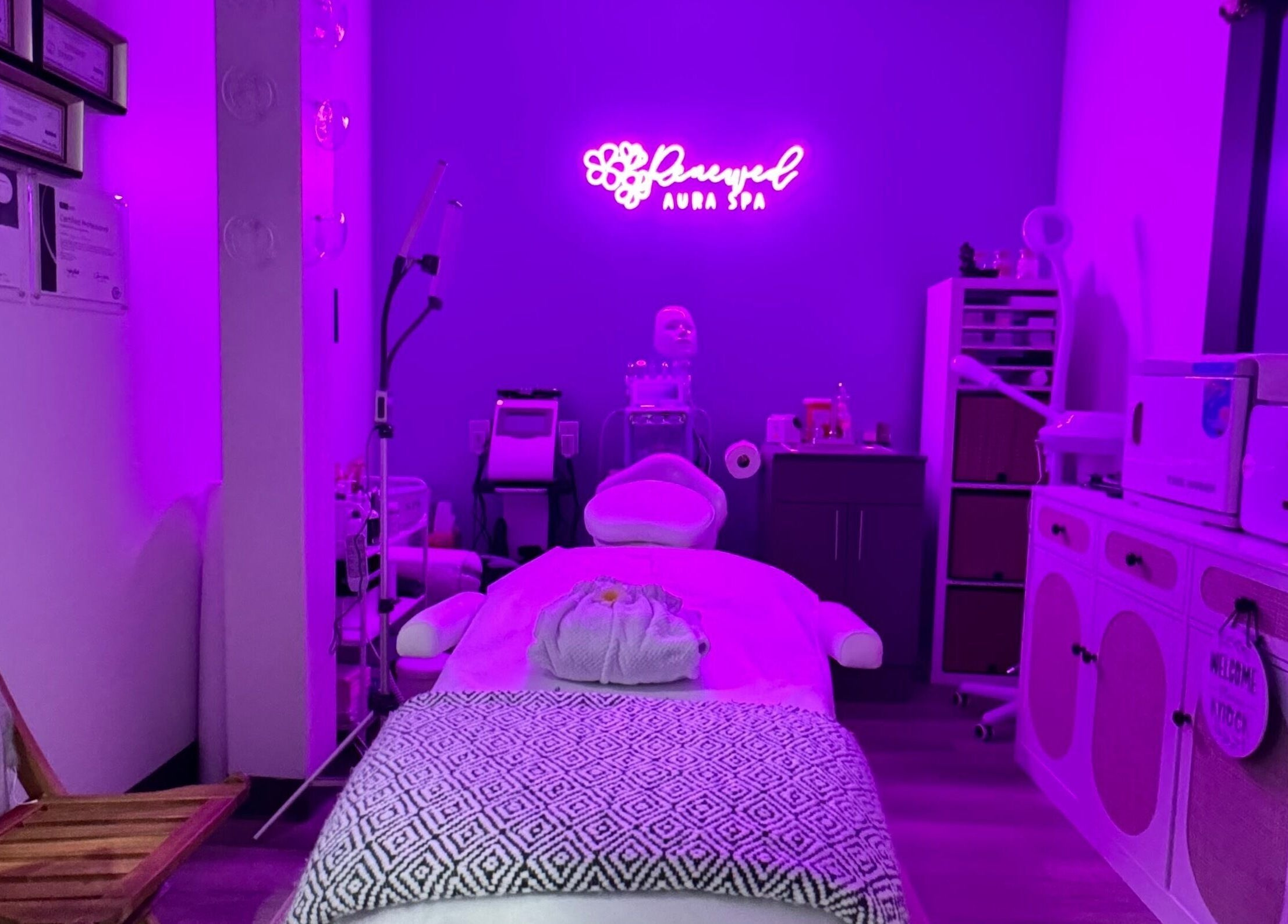 Relaxing treatment room at RAS in Gainesville, Virginia, US, with ambient purple lighting and skincare equipment.