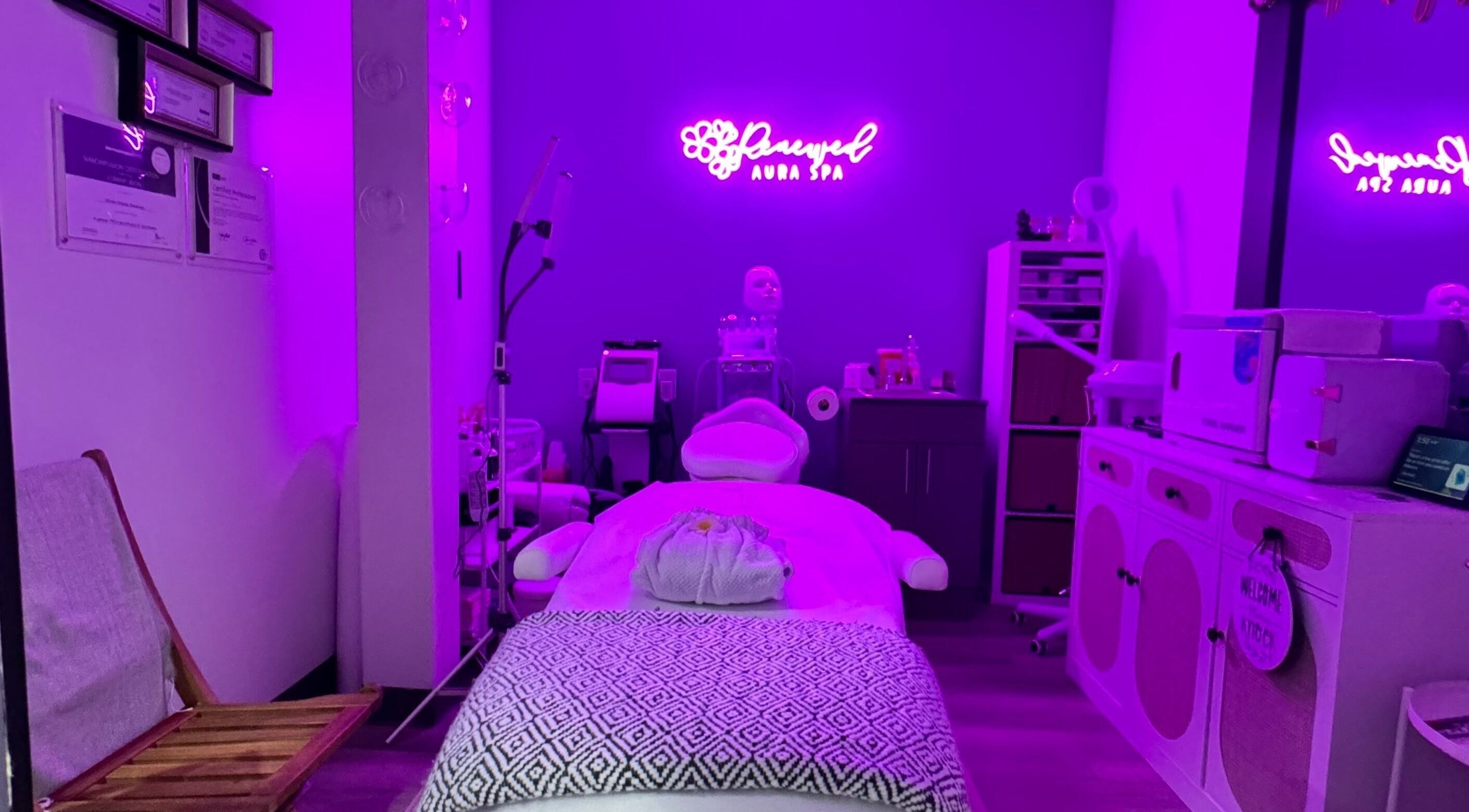 Relaxing treatment room at RAS in Gainesville, Virginia, US, with ambient purple lighting and skincare equipment.