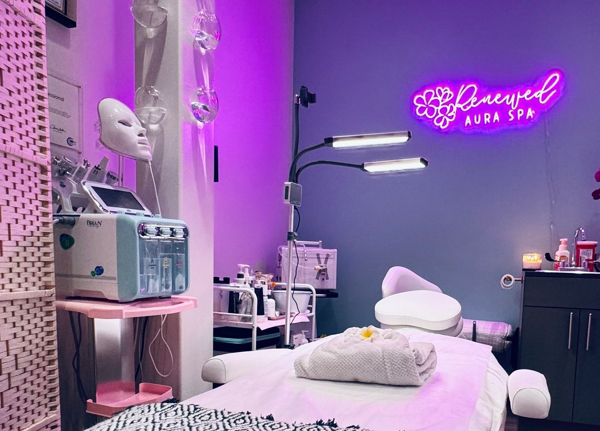 Relaxing spa room with treatment bed at RAS, Gainesville, Virginia, US, featuring ambient purple lighting.