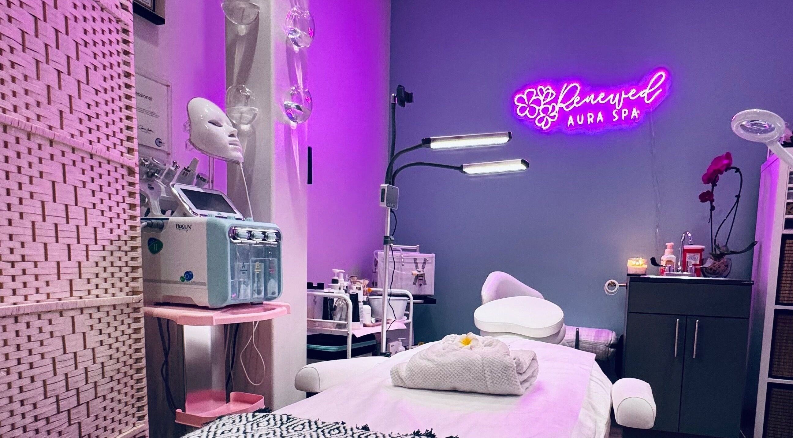 Relaxing spa room at RAS in Gainesville, Virginia, US with pink lighting and modern facial equipment.