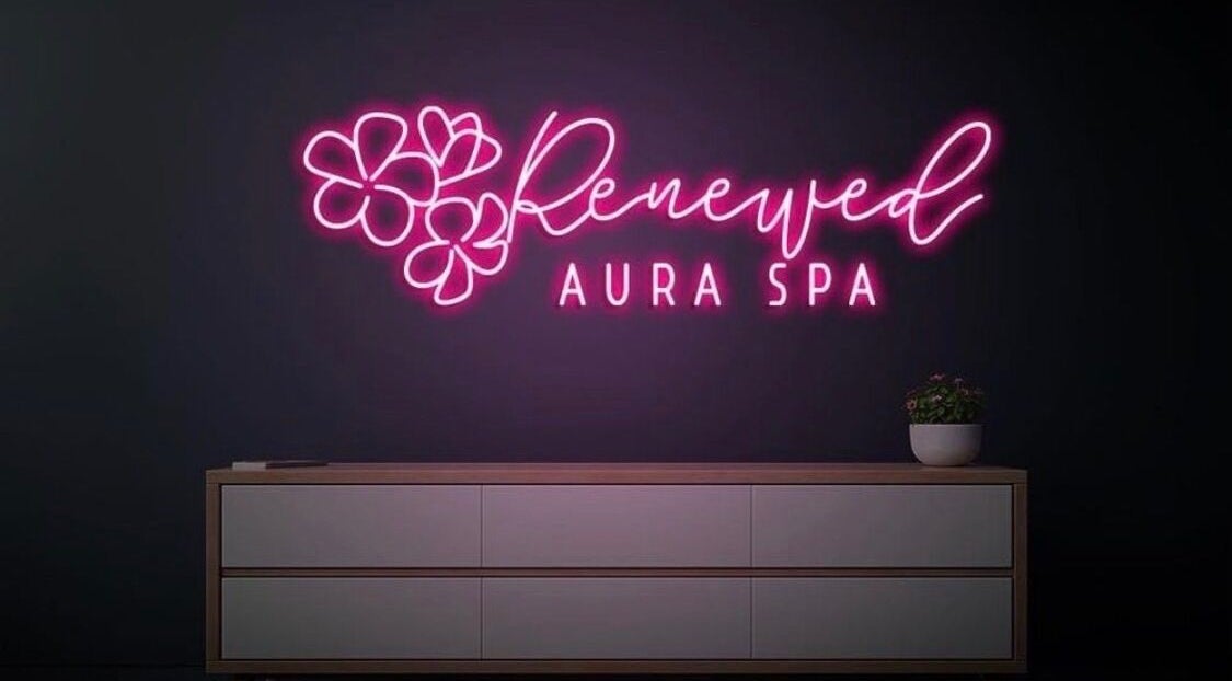Bright pink neon sign of RAS spa in Gainesville, Virginia, US with floral accents on a sleek wall.