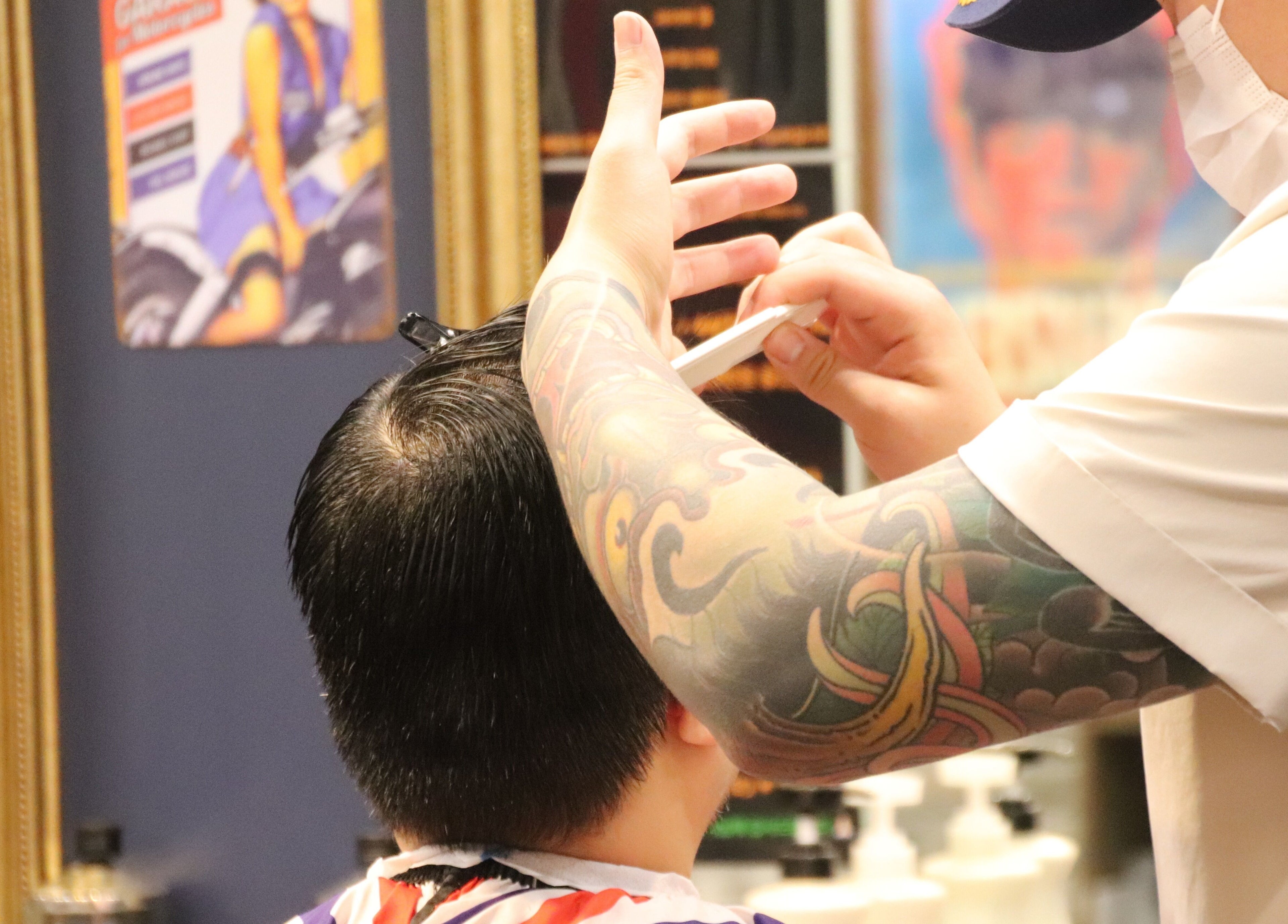 Tattooed barber skillfully cutting hair at US Barbershop, 서울특별시, 서울특별시, KR.