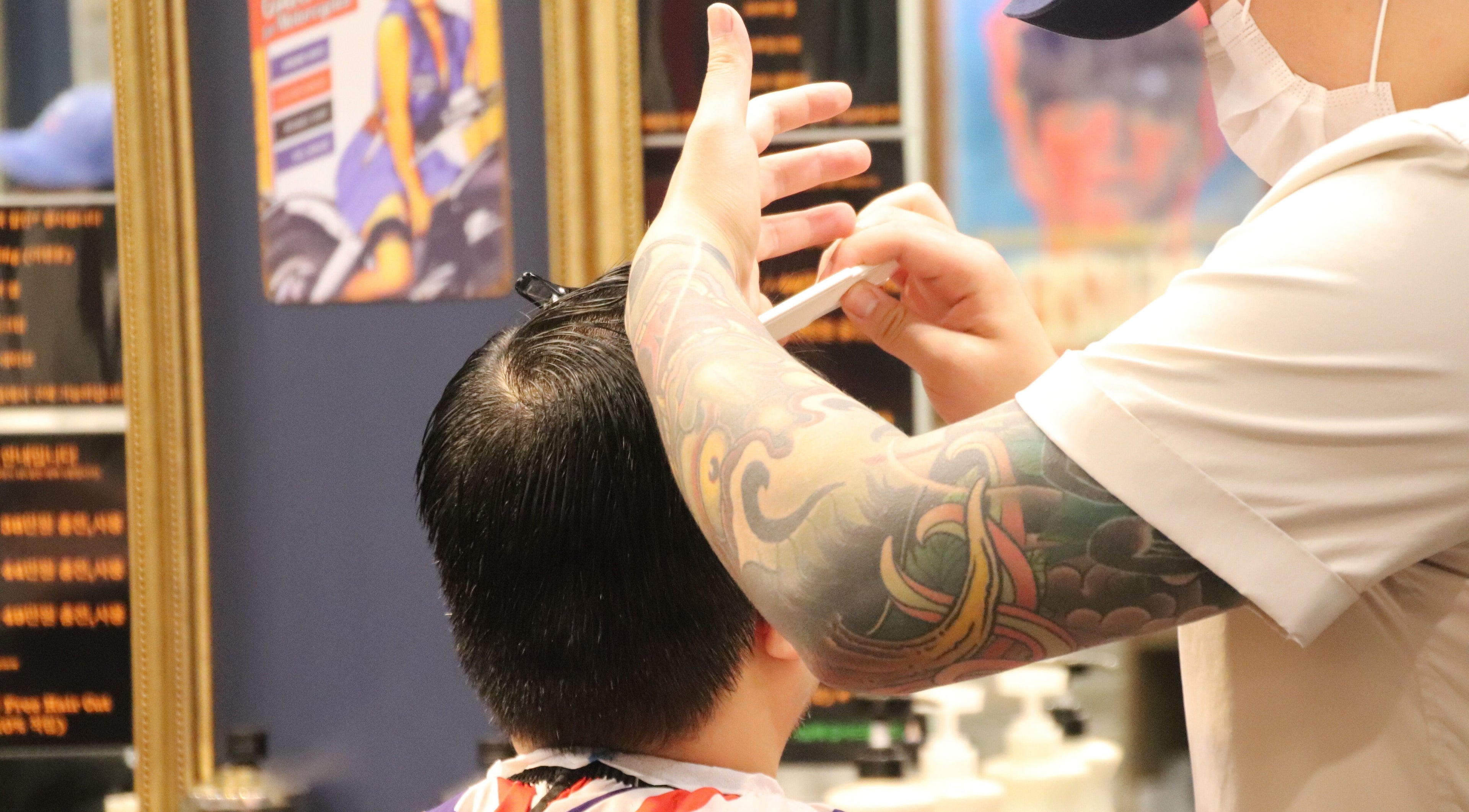 Tattooed barber skillfully cutting hair at US Barbershop, 서울특별시, 서울특별시, KR.