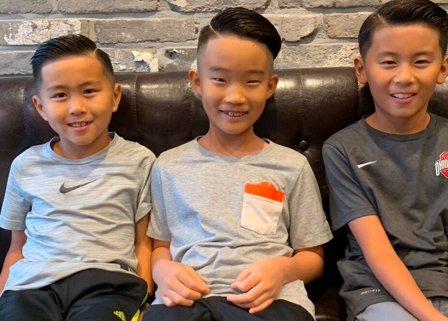 Young boys with stylish haircuts at US Barbershop, 서울특별시, 서울특별시, KR, sitting happily on a couch.