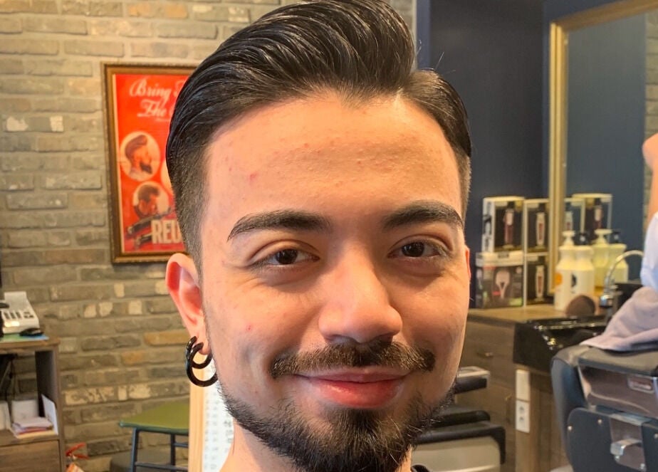 Smiling man at US Barbershop in 서울특별시, KR, showcasing a stylish haircut and cozy interior.