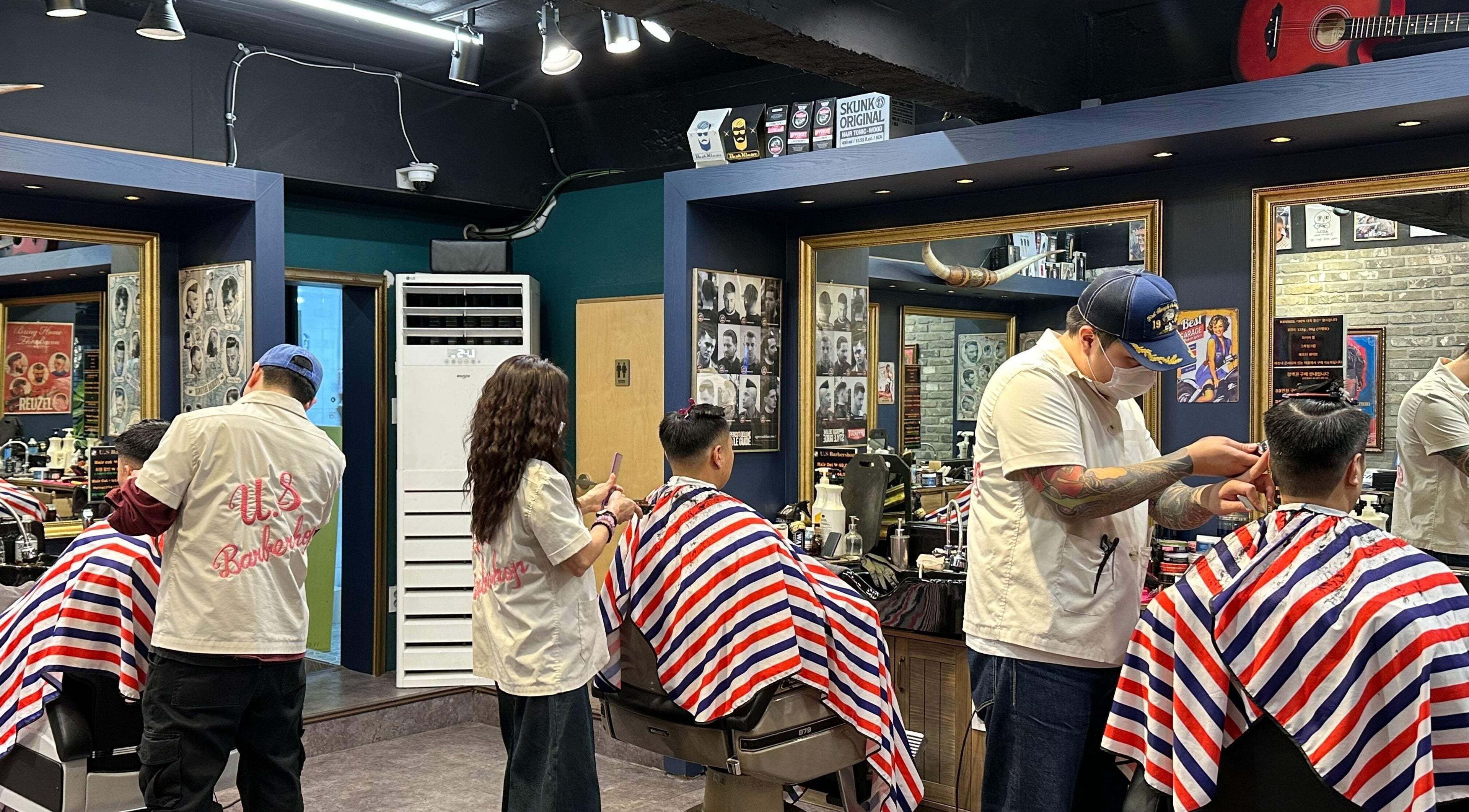 Barbers styling hair at US Barbershop in 서울특별시, 서울특별시, KR with vibrant decor.