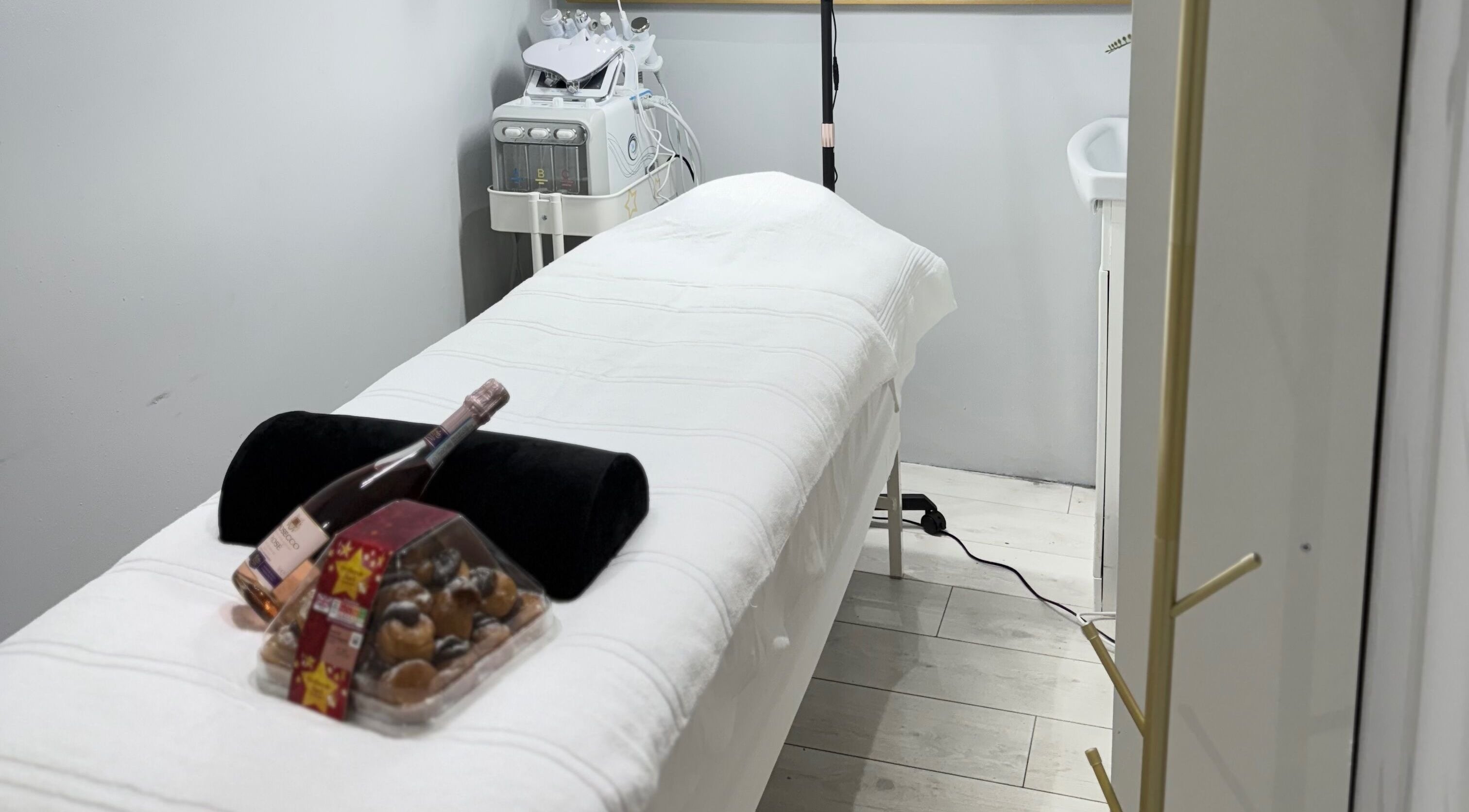 Luxury treatment room at SkinSociety, Sutton, England, GB featuring massage table with bottled drink and confections.