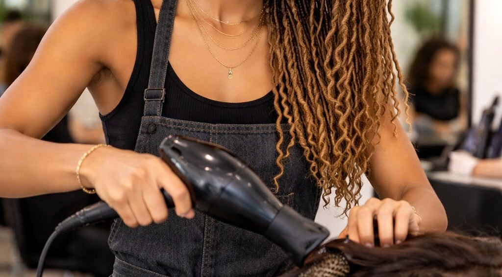 Professional hairstylist at Shanzz_beauty_box in Oistins, Christ Church, BB expertly blow-drying hair.