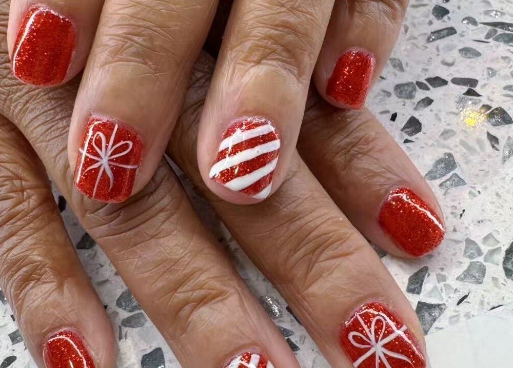 Red glitter nails with festive designs at Yoyo Nails, Noblesville, Indiana, US.