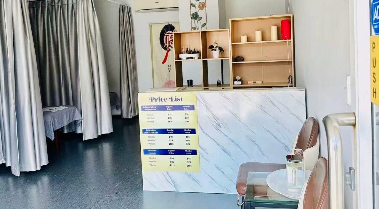 Reception area of Rosedale Traditional Massage, Auckland, NZ with price list and cozy seating.