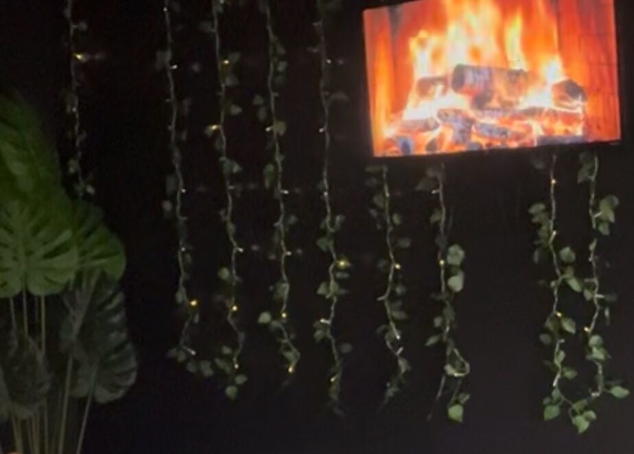 A cozy fireplace ambiance at Velour Men’s Spa in Atlanta, Georgia, US, with hanging green vines.