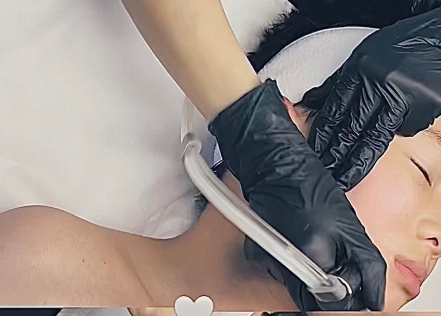 Facial treatment at M.N.M Beauty Bar, Roselands, New South Wales, AU. Hands in black gloves pampering skin.