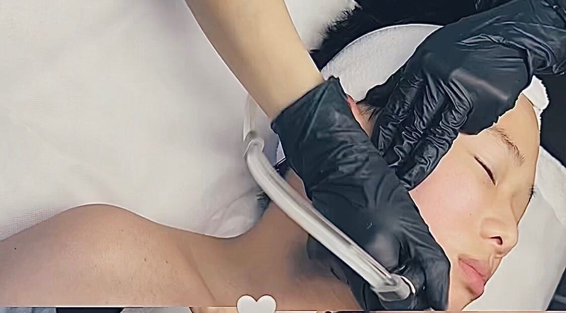 Facial treatment at M.N.M Beauty Bar, Roselands, New South Wales, AU. Hands in black gloves pampering skin.