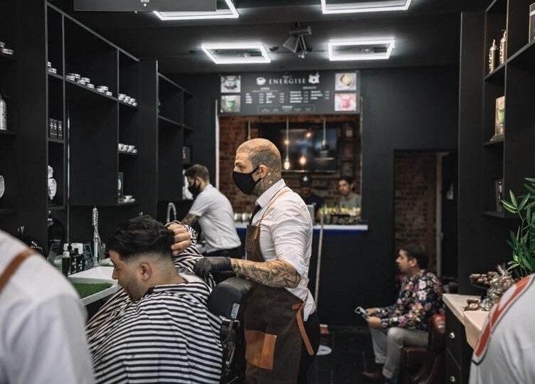 Barber styling a client's hair at Bar Bar Co, Brentwood, England, GB. A chic venue with modern interior.
