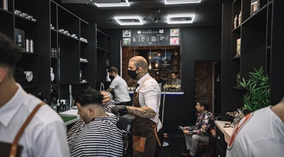 Barber styling a client's hair at Bar Bar Co, Brentwood, England, GB. A chic venue with modern interior.