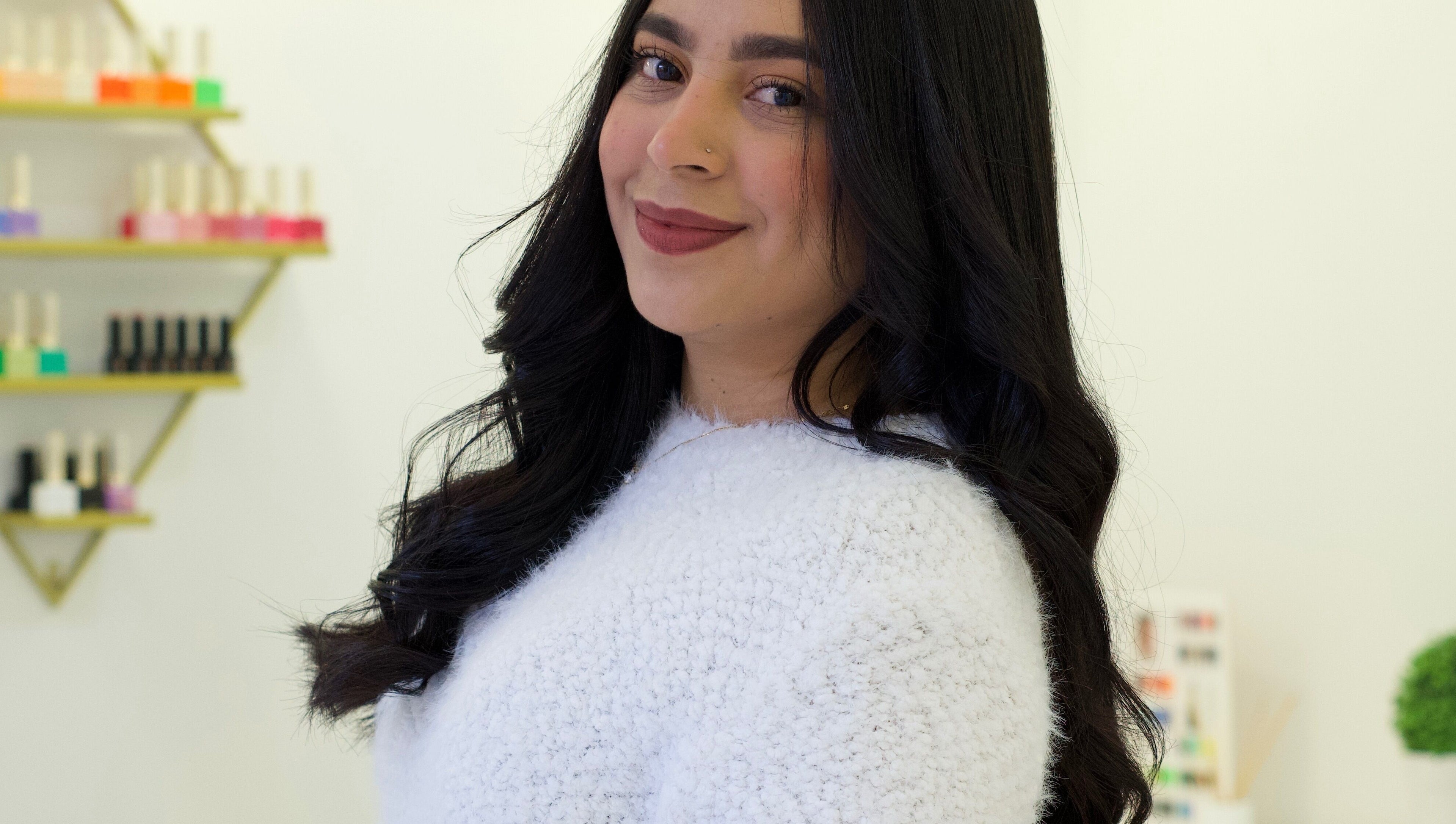 Smiling woman at AleStudioNails in Santiago Y Zaraíche, Región De Murcia, ES, with nail polish display.