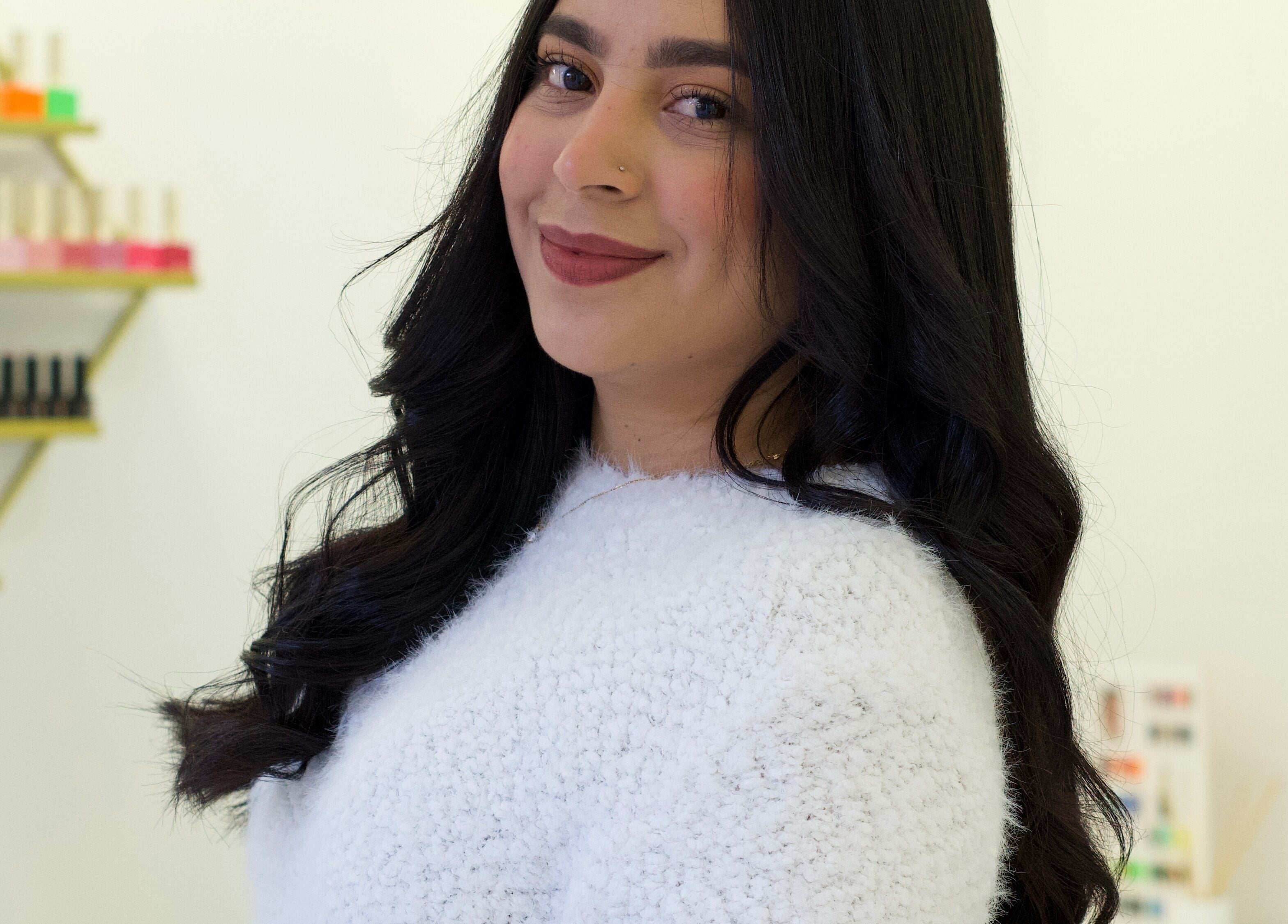 Smiling woman at AleStudioNails in Santiago Y Zaraíche, Región De Murcia, ES, with nail polish display.