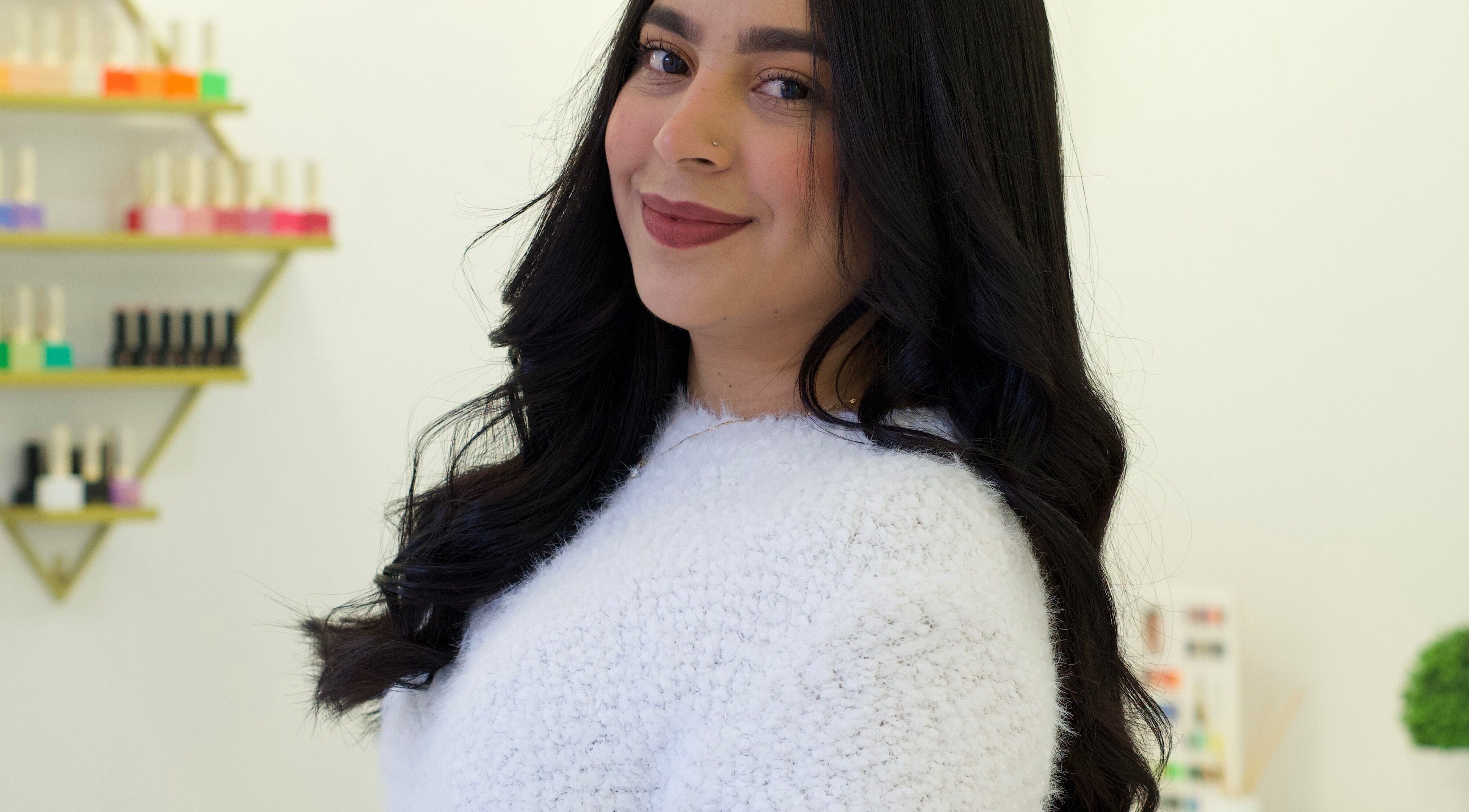 Smiling woman at AleStudioNails in Santiago Y Zaraíche, Región De Murcia, ES, with nail polish display.