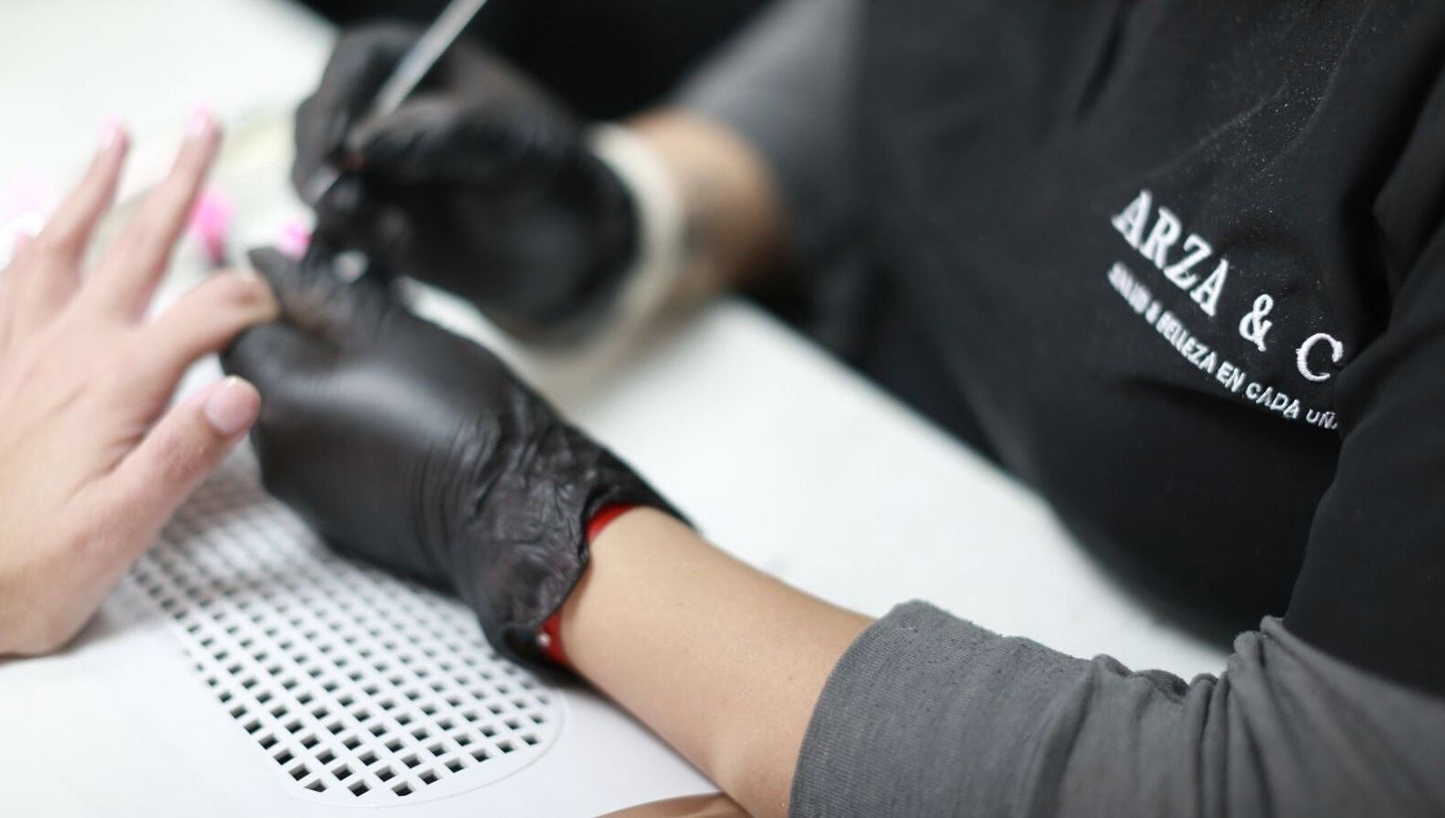 Nail artist at Arza & Co in Ciudad De México, MX expertly painting a client's nails.