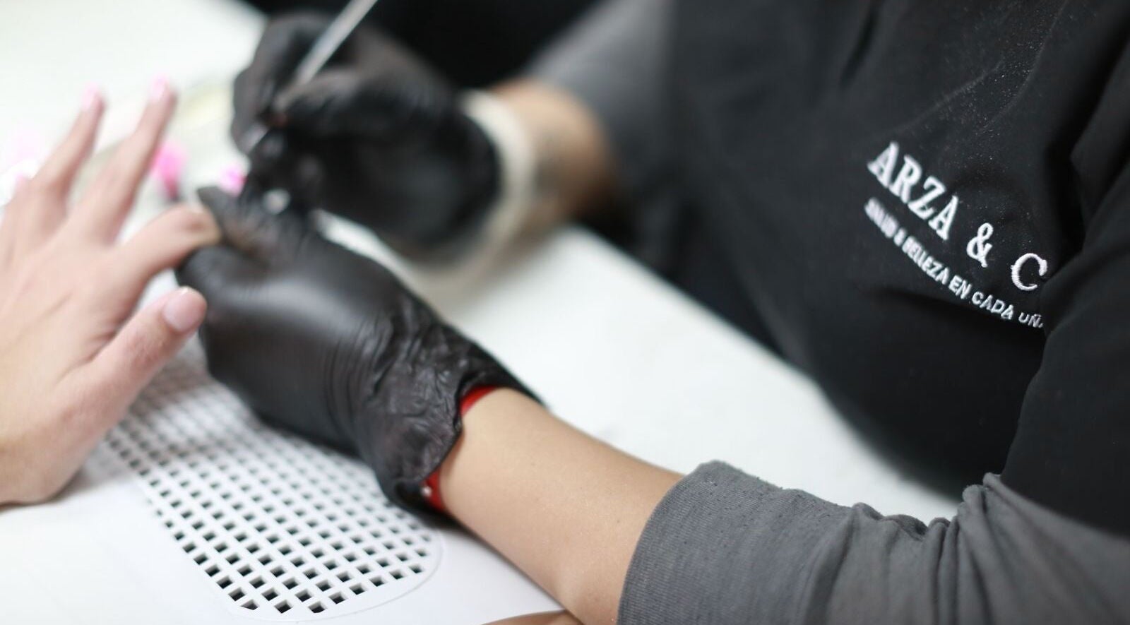 Nail artist at Arza & Co in Ciudad De México, MX expertly painting a client's nails.